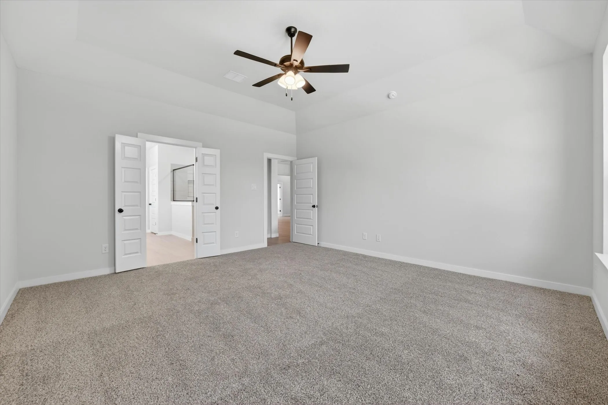 Spacious room featuring vaulted ceilings, neutral-toned carpet flooring, and white walls