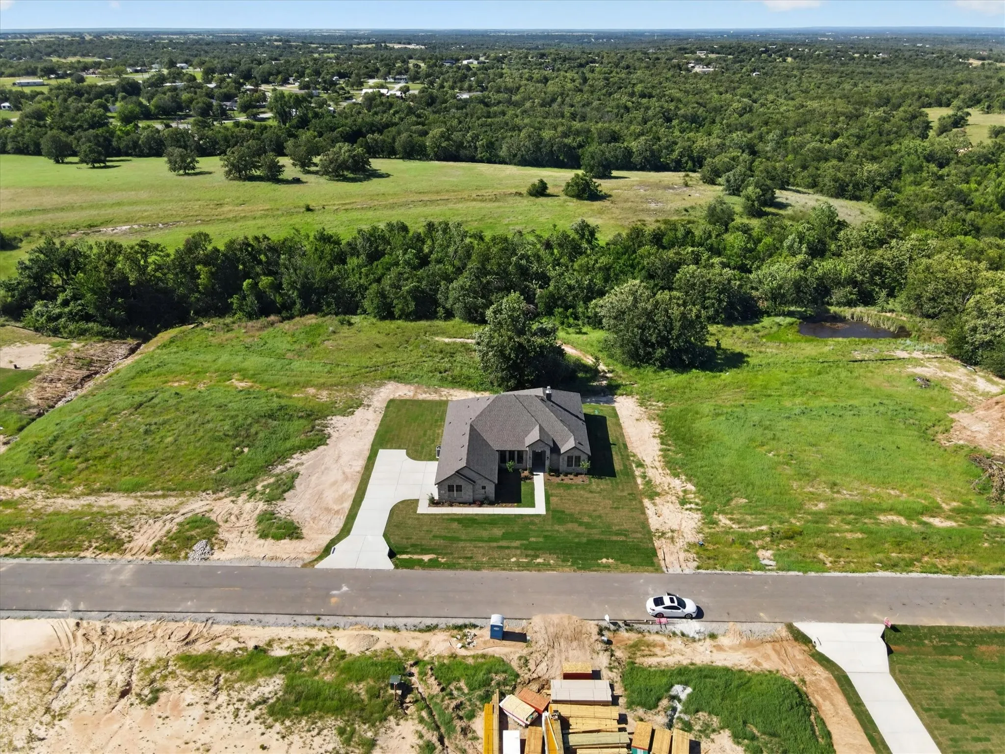 Modern home featuring a light gray exterior with stone accents, a dark shingle roof, and a concrete driveway