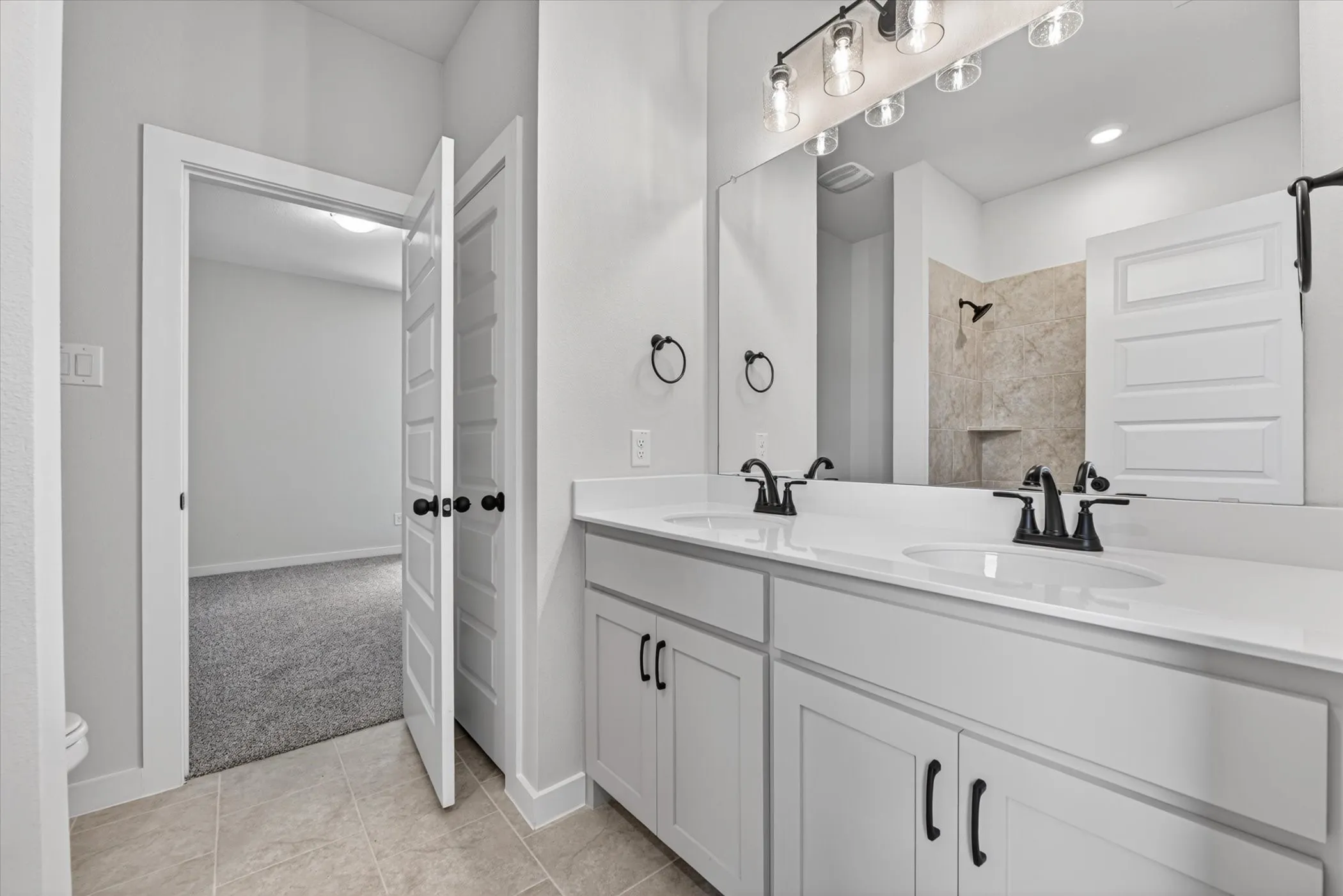 Dual vanity with white cabinetry, matte black fixtures, and a spacious mirror