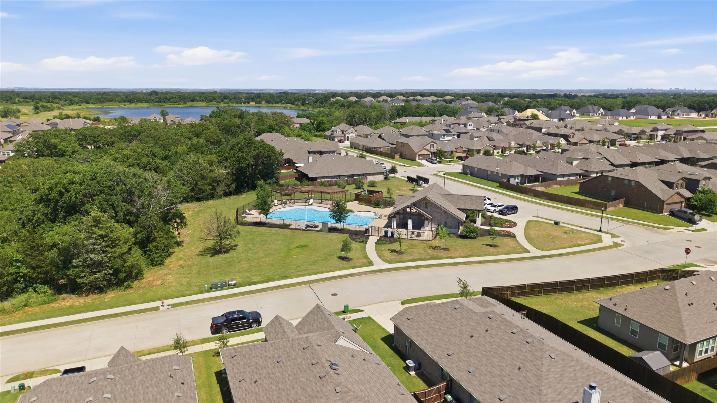 Community amenity center featuring a swimming pool, covered patio, and manicured landscaping