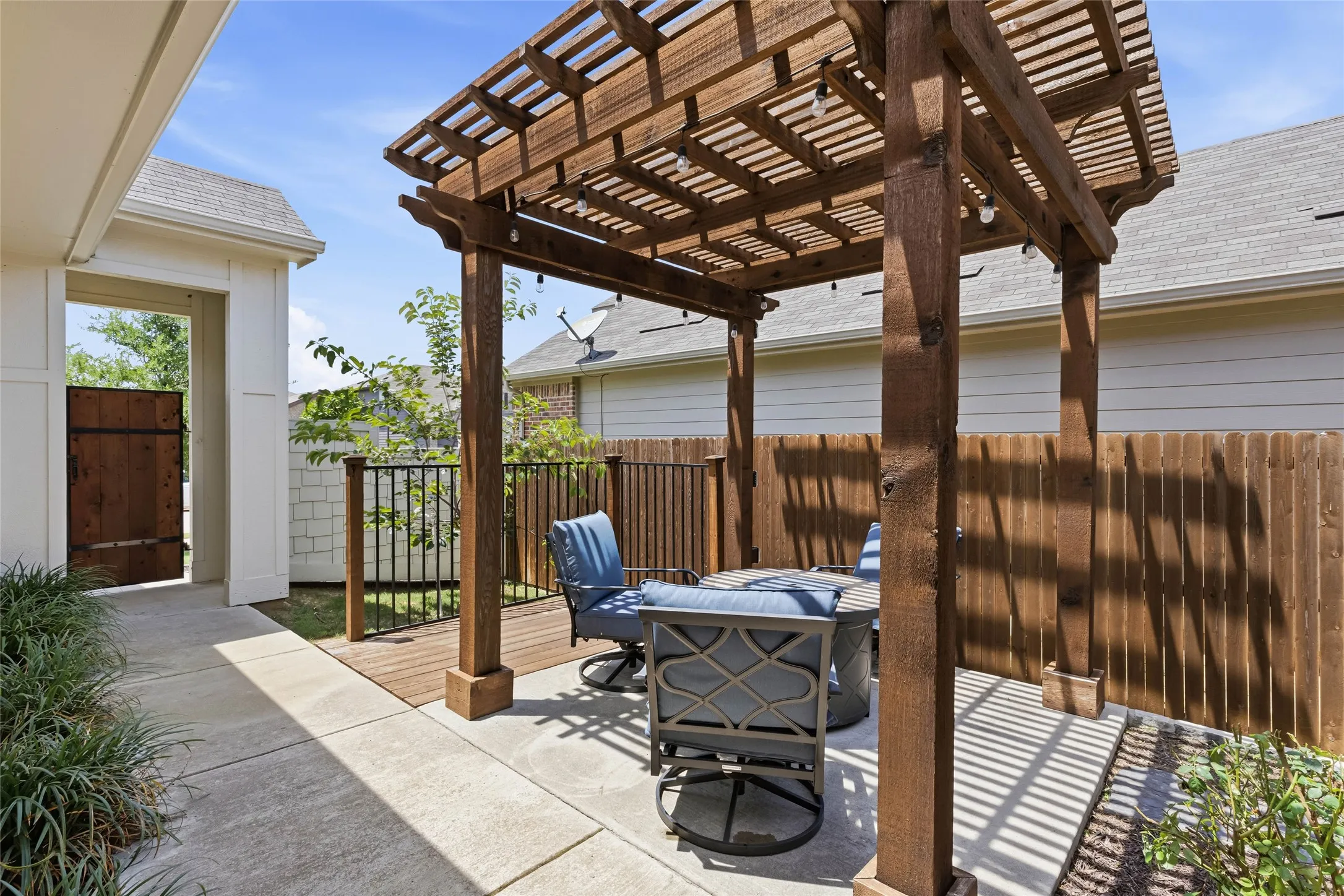 Outdoor patio featuring a wooden pergola with string lighting