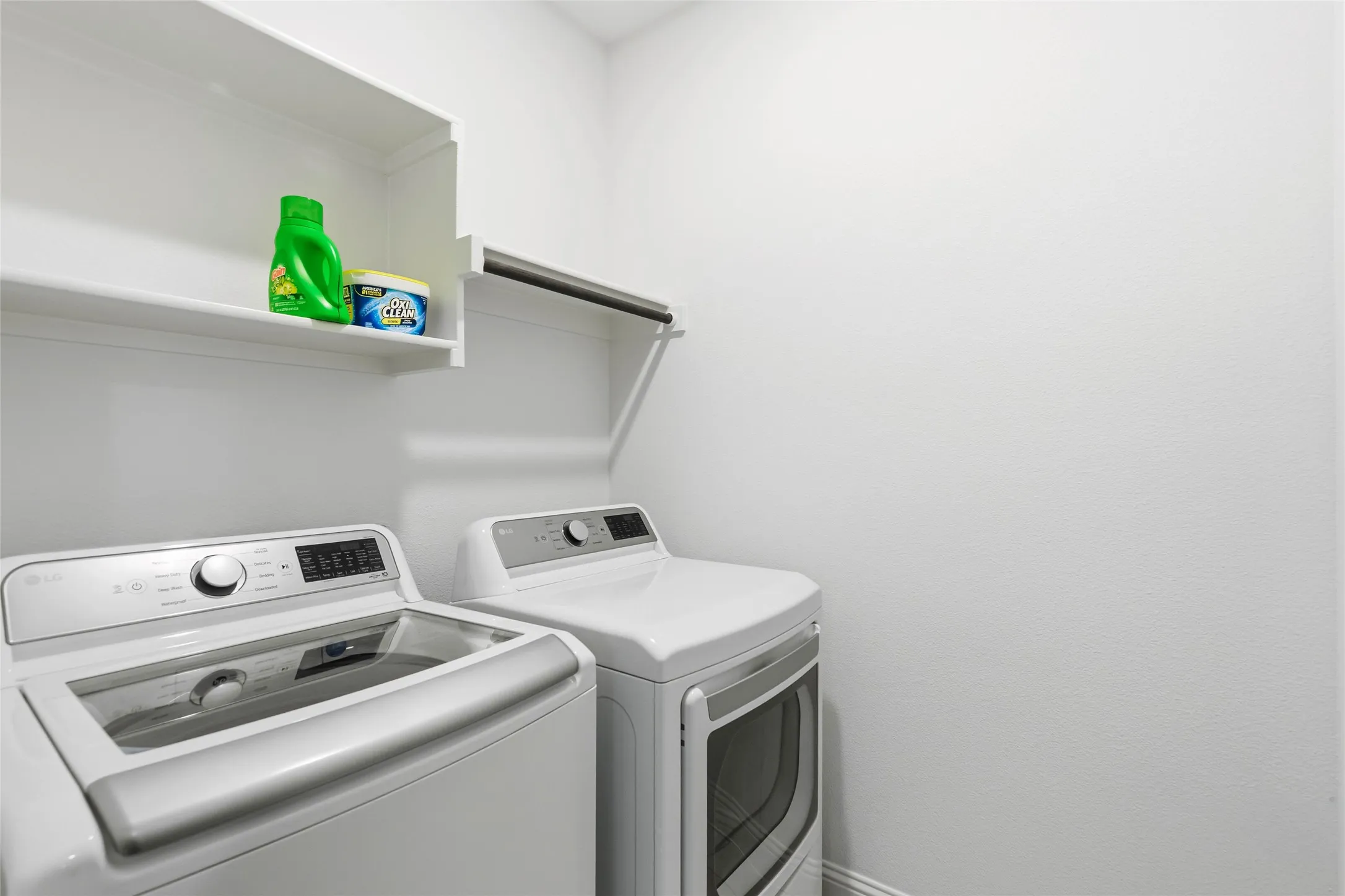 Dedicated laundry area featuring white walls, an upper storage shelf, and a clothing rod