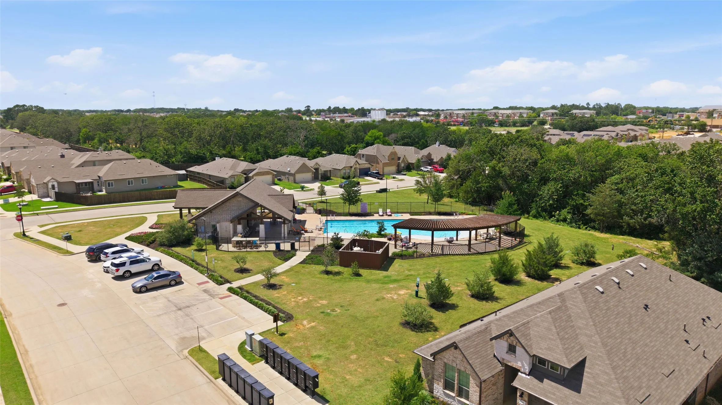 Community pool with a shaded gathering area, surrounded by green space