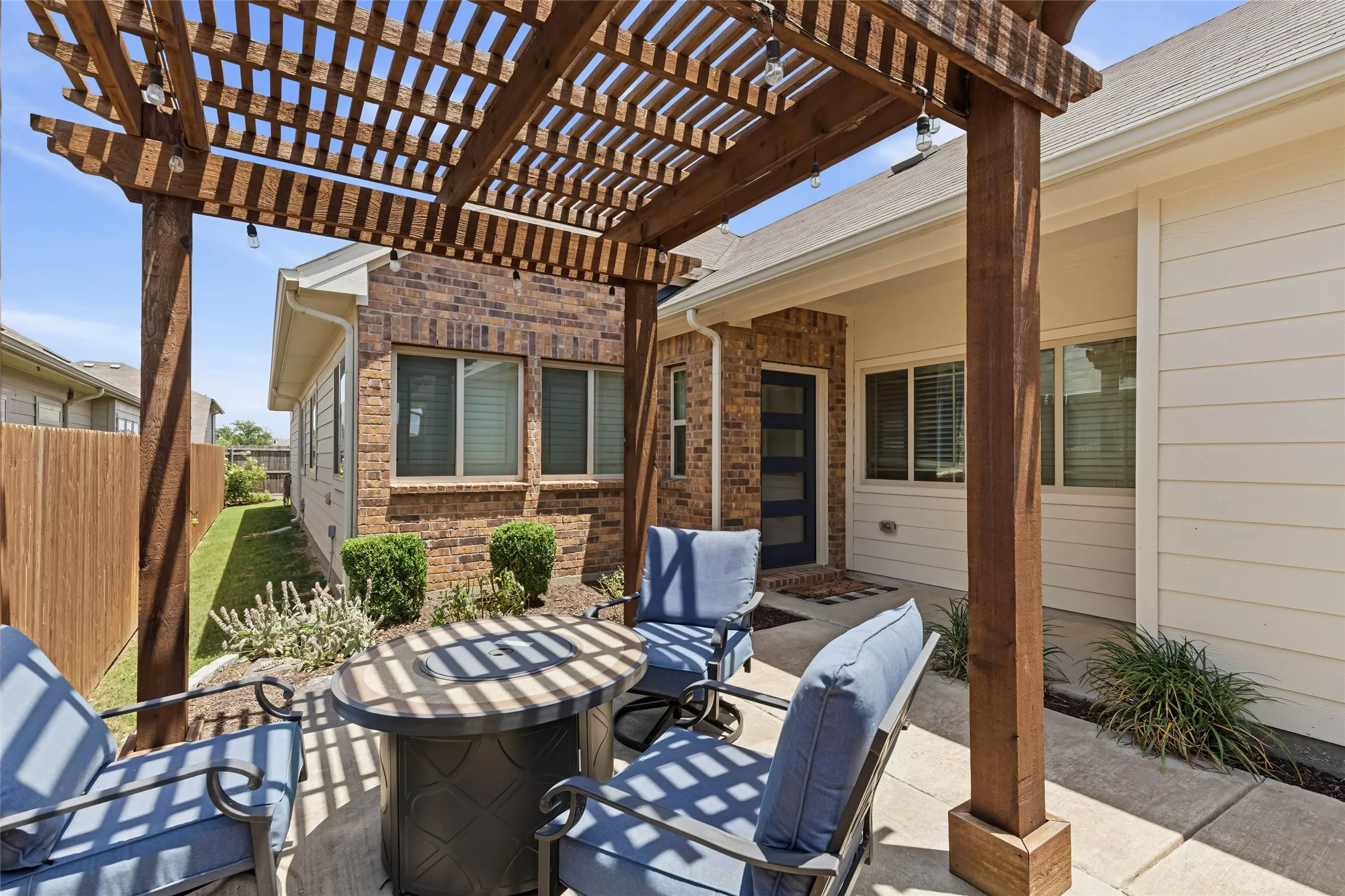 Outdoor pergola with string lights providing shade over a concrete patio