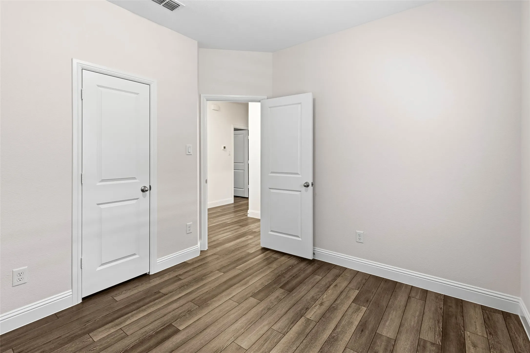Spacious room with wood-finish flooring, light-toned walls, and white trim