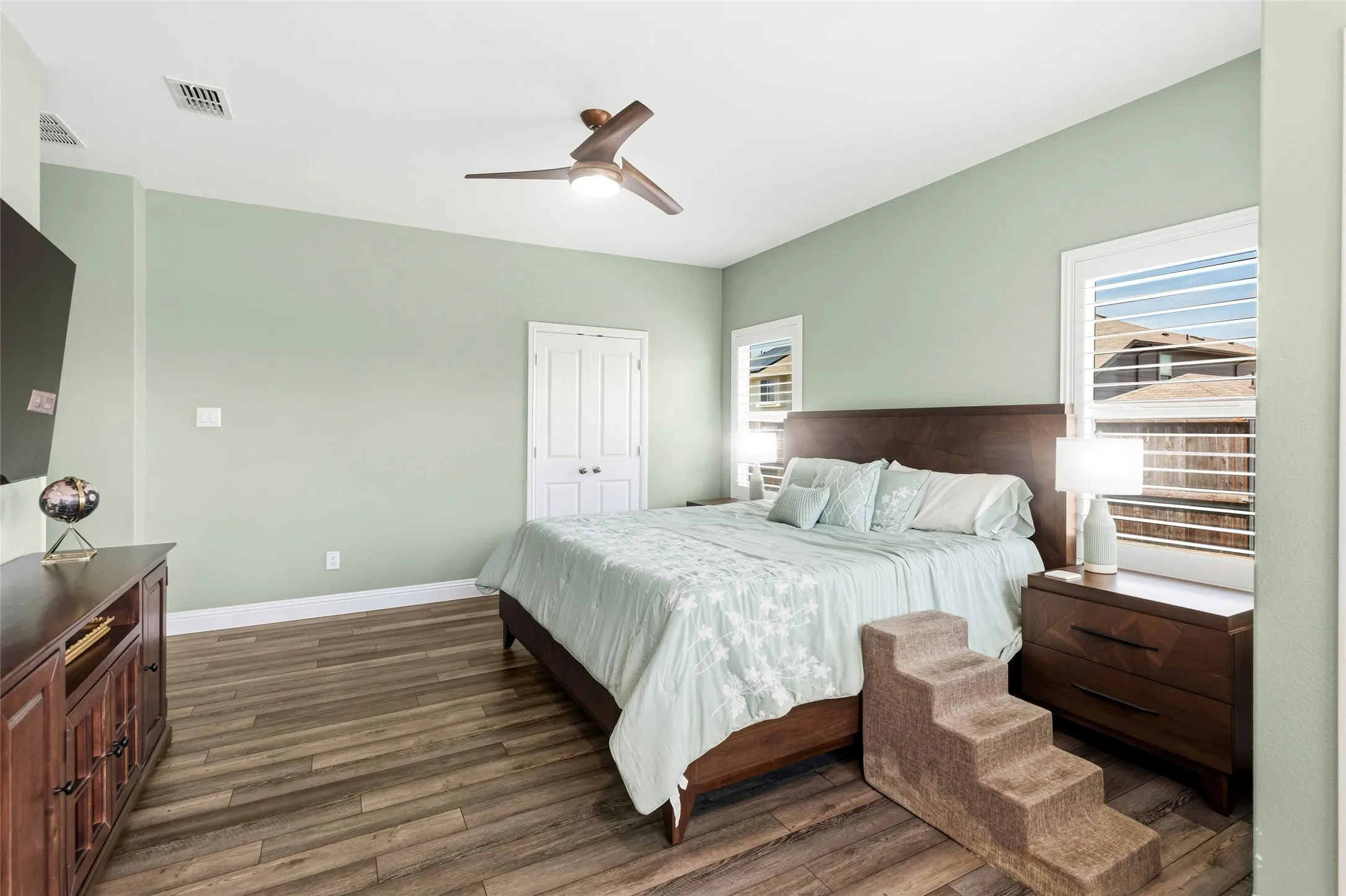 Spacious room featuring wood-finish flooring, a contemporary ceiling fan, and light green wall paint