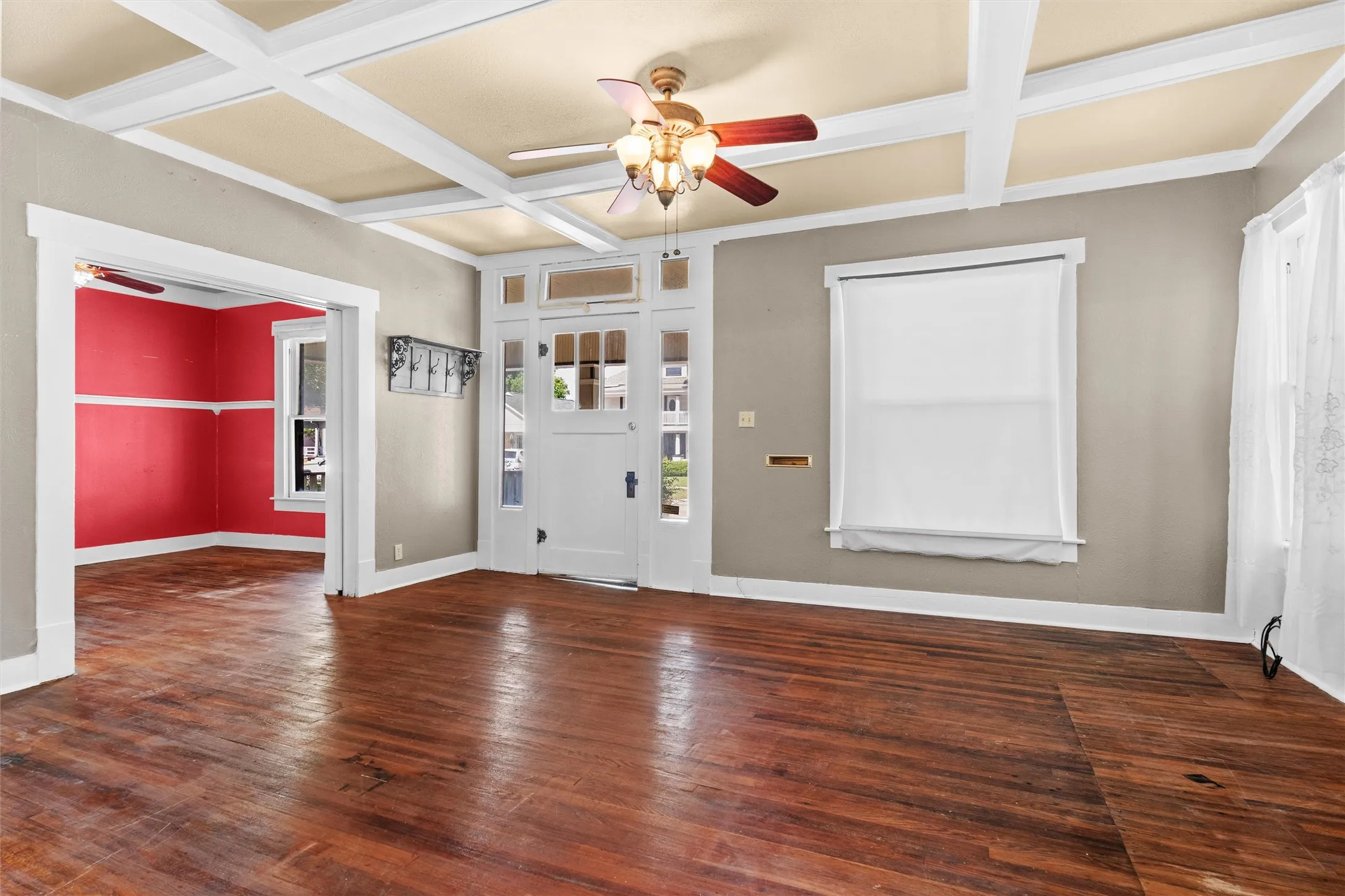Spacious interior featuring wood-finish flooring, a coffered ceiling, and a prominent entry door with transom and side-light windows