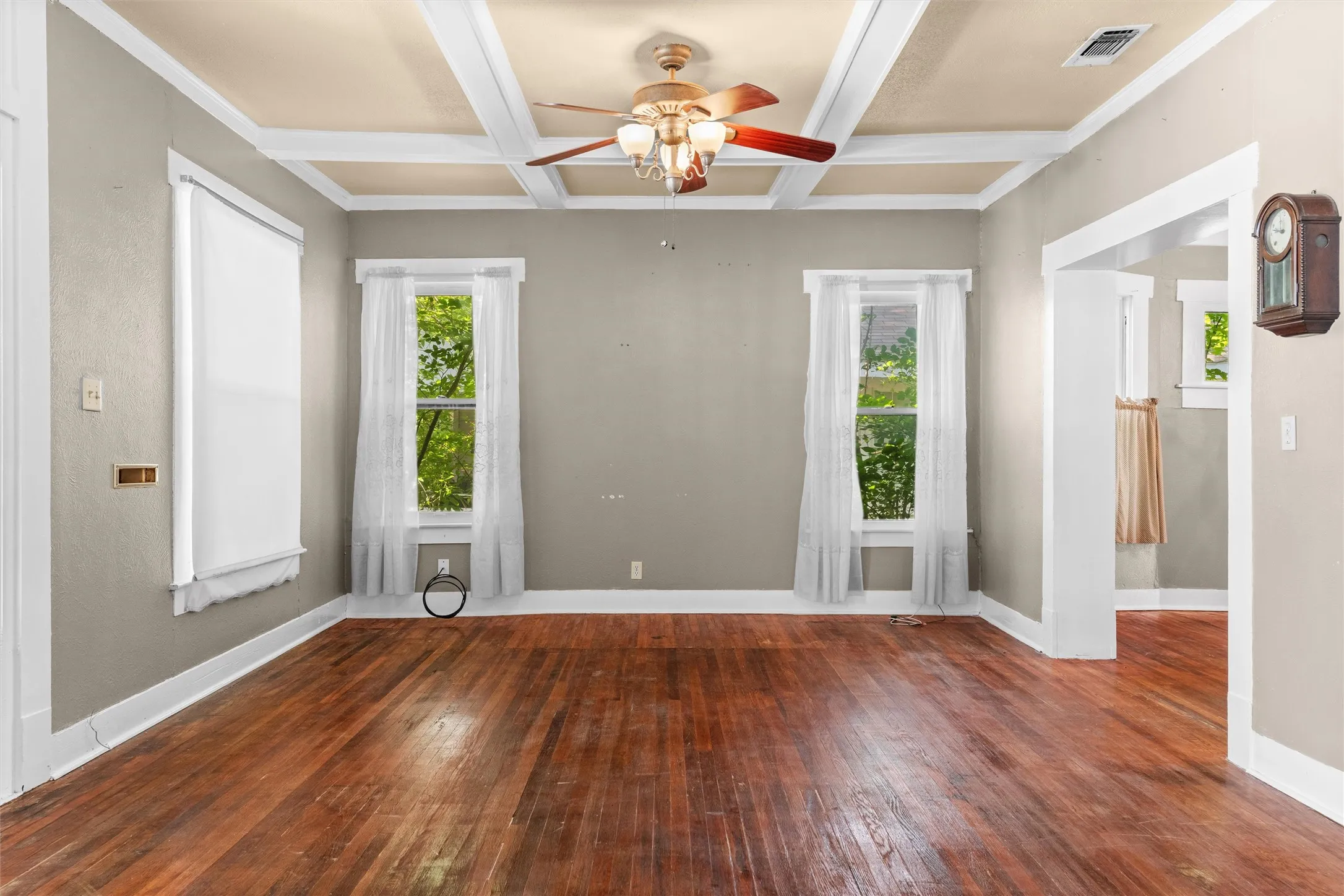 Living space featuring coffered ceilings, wood-finish flooring, and multiple windows