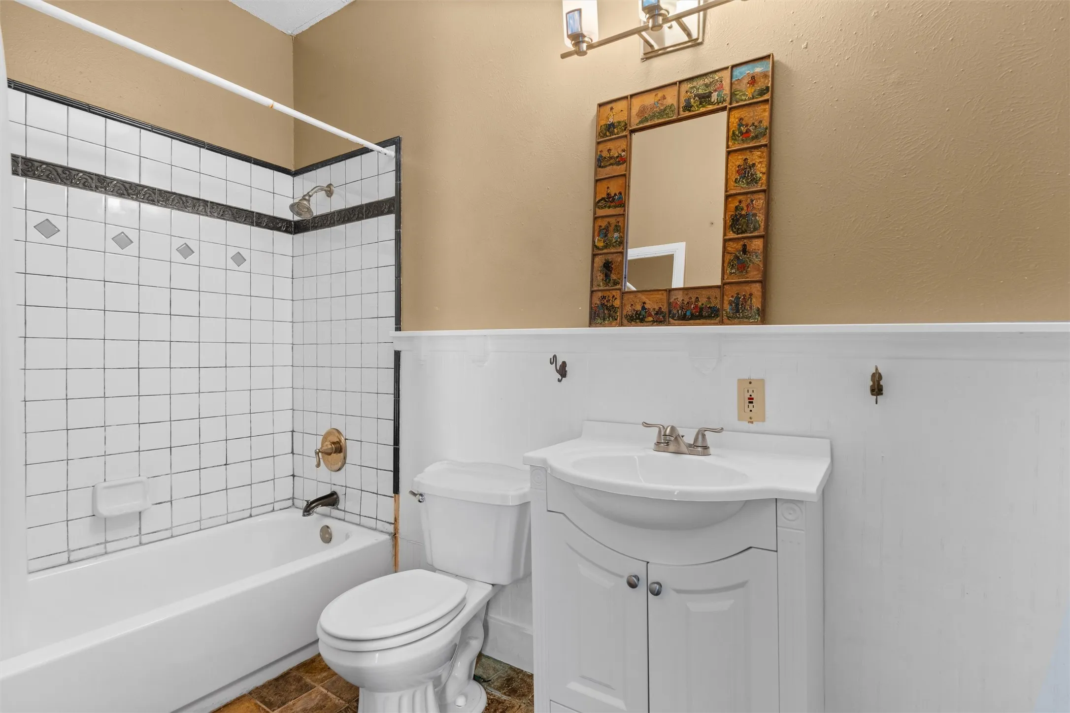 Bathroom featuring a white vanity with integrated sink, brushed nickel faucet, a white toilet, and a white bathtub with a tiled shower surround