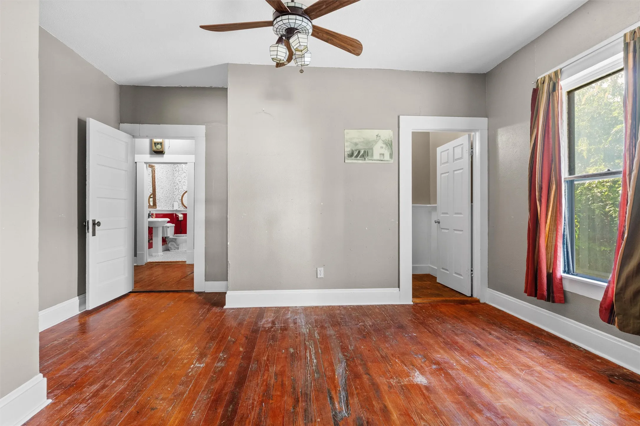 Room featuring wood-finish flooring, a ceiling fan with integrated lighting, and neutral wall paint