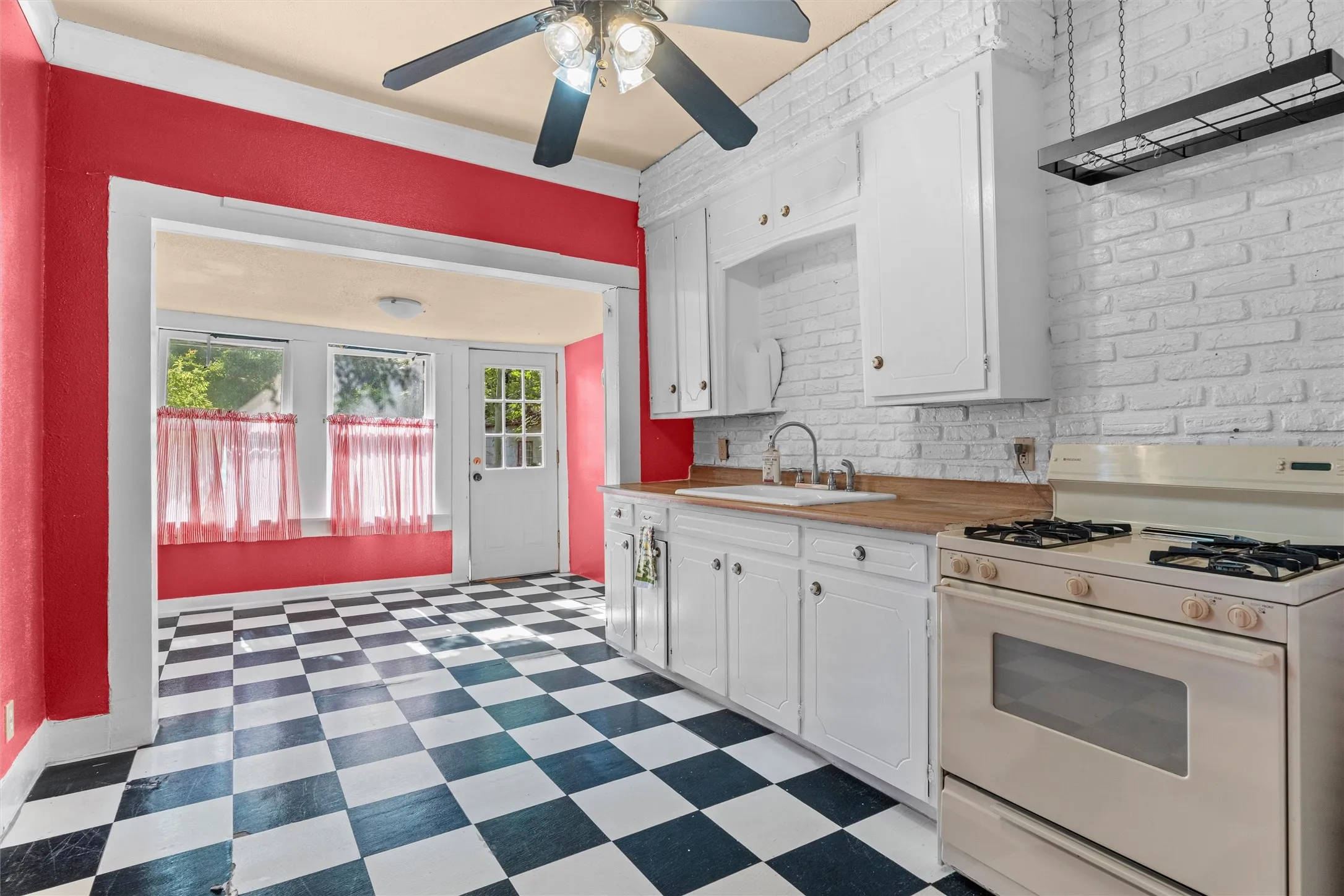 Kitchen featuring white cabinetry, wood-finish countertops, and a white freestanding gas range