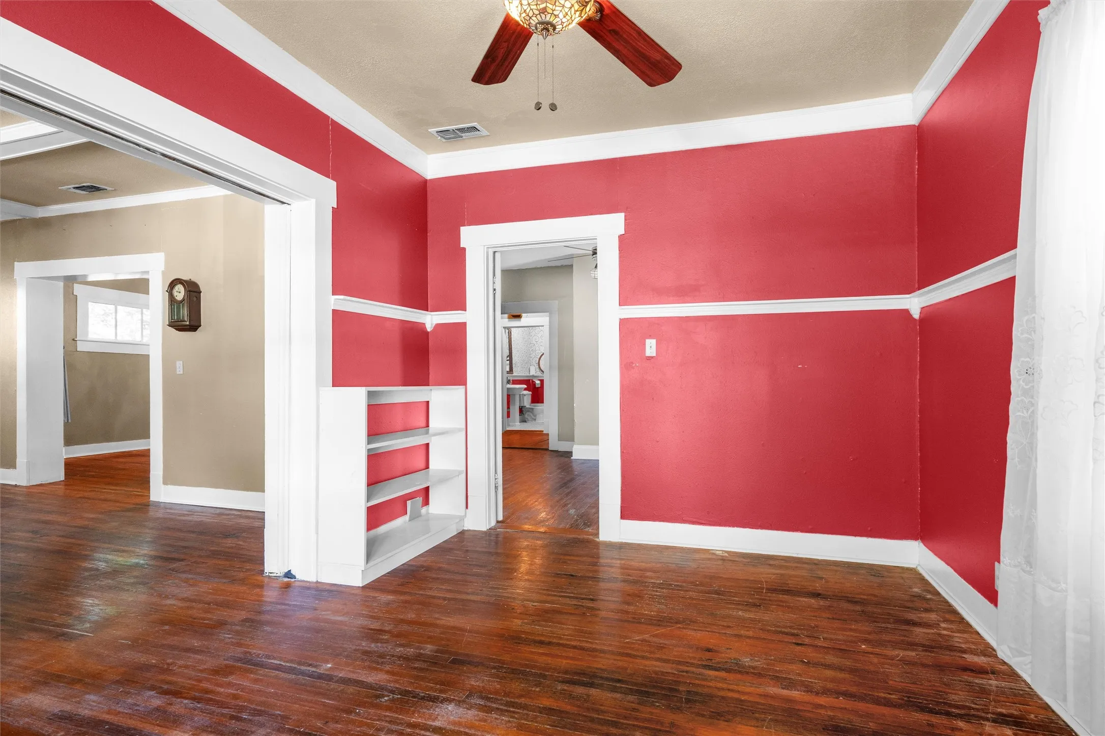 Spacious interior with rich wood-finish flooring, high ceilings, and a detailed ceiling fan fixture