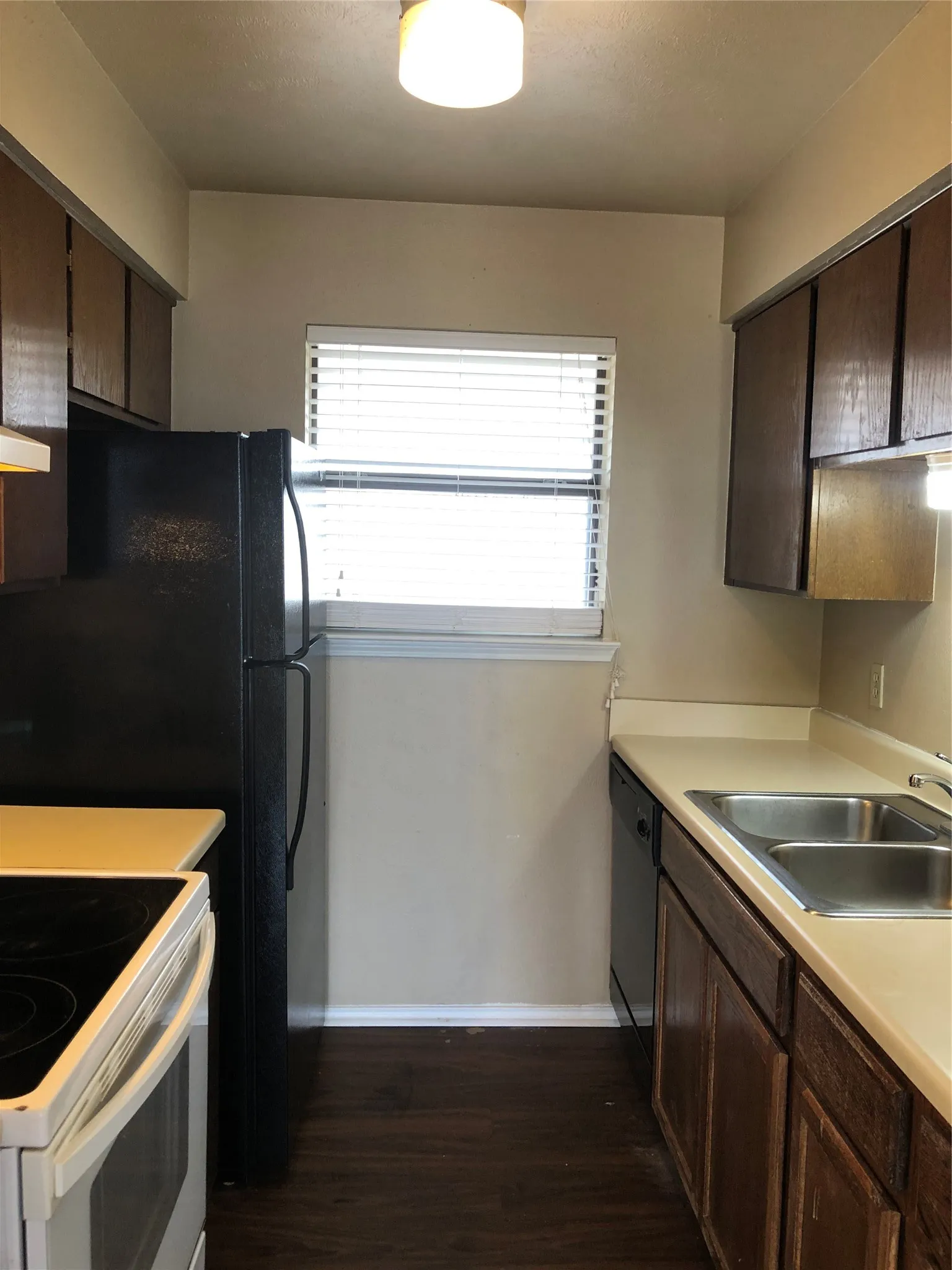 This efficient galley kitchen is fully equipped with rich dark cabinetry, essential appliances, and a bright window that keeps your cooking space light and airy.