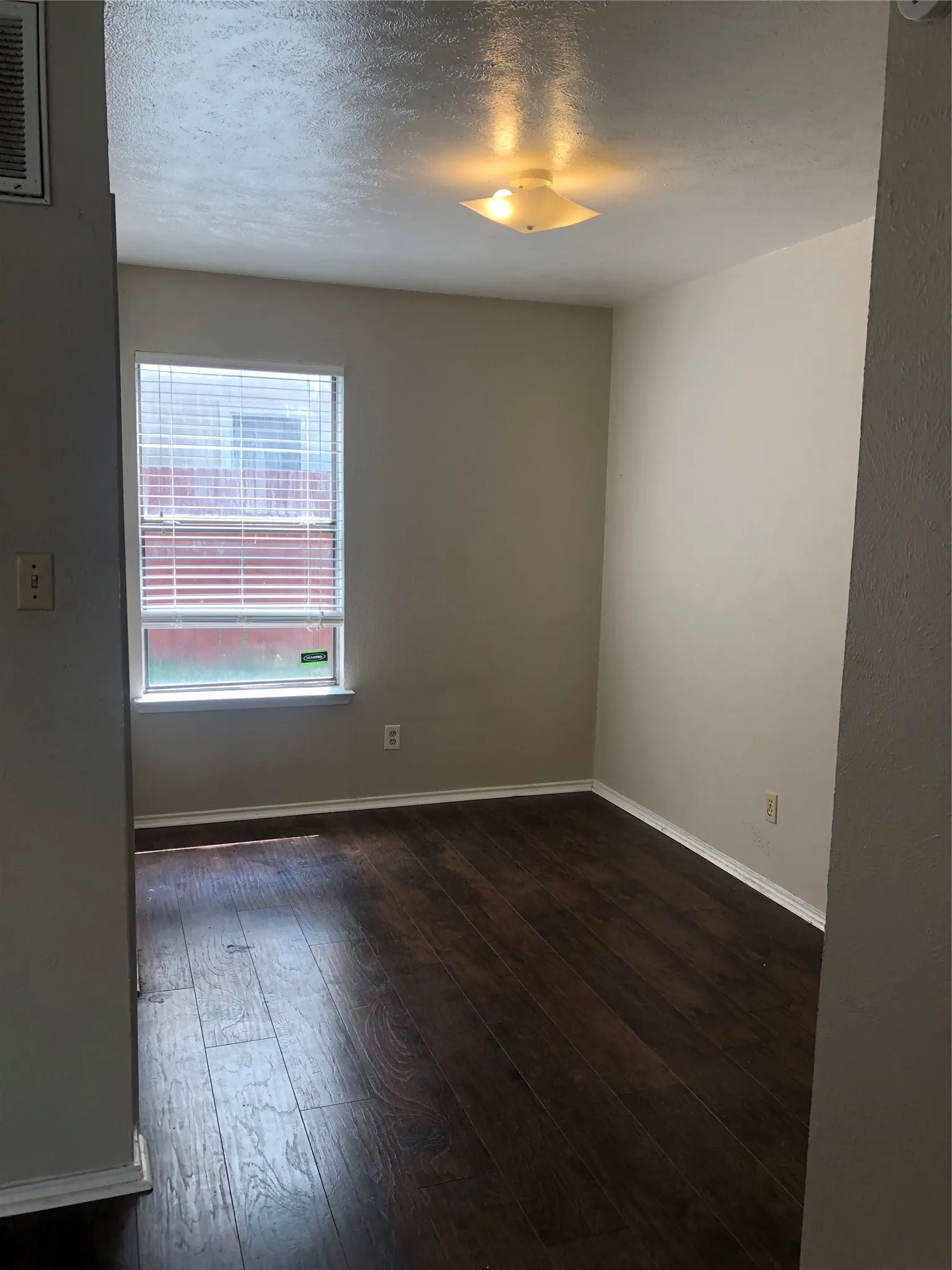 Retreat to a quiet, cozy bedroom showcasing stylish dark wood-look floors and a bright window that fills the room with warm, natural light. It offers a peaceful personal sanctuary to unwind and recharge at the end of the day.