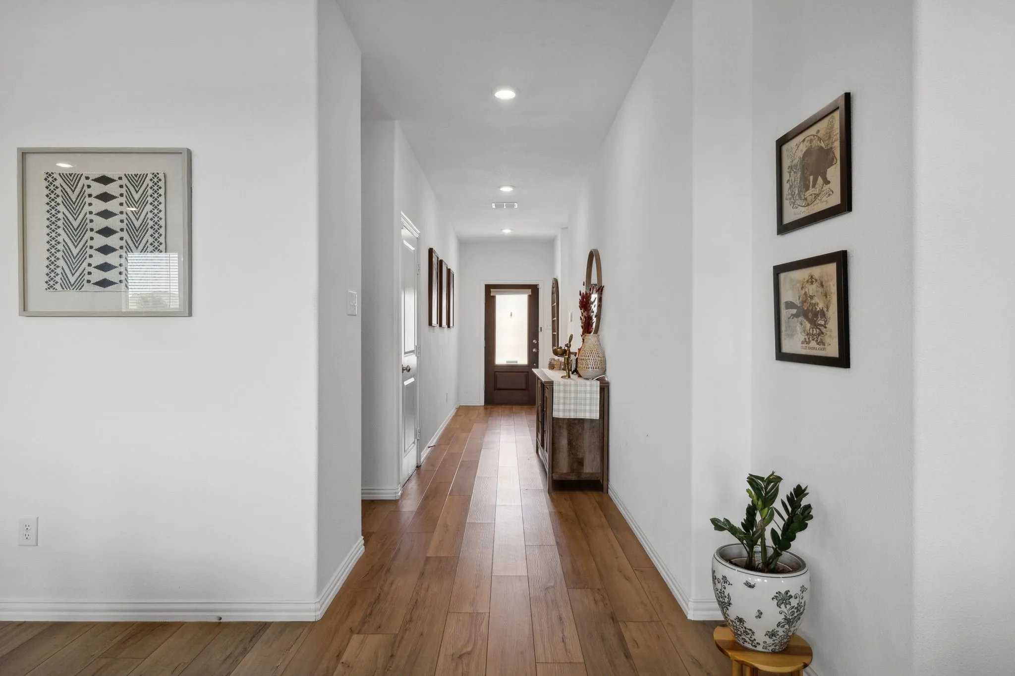 Hallway featuring wood-finish flooring, white baseboards, recessed lighting, and white walls