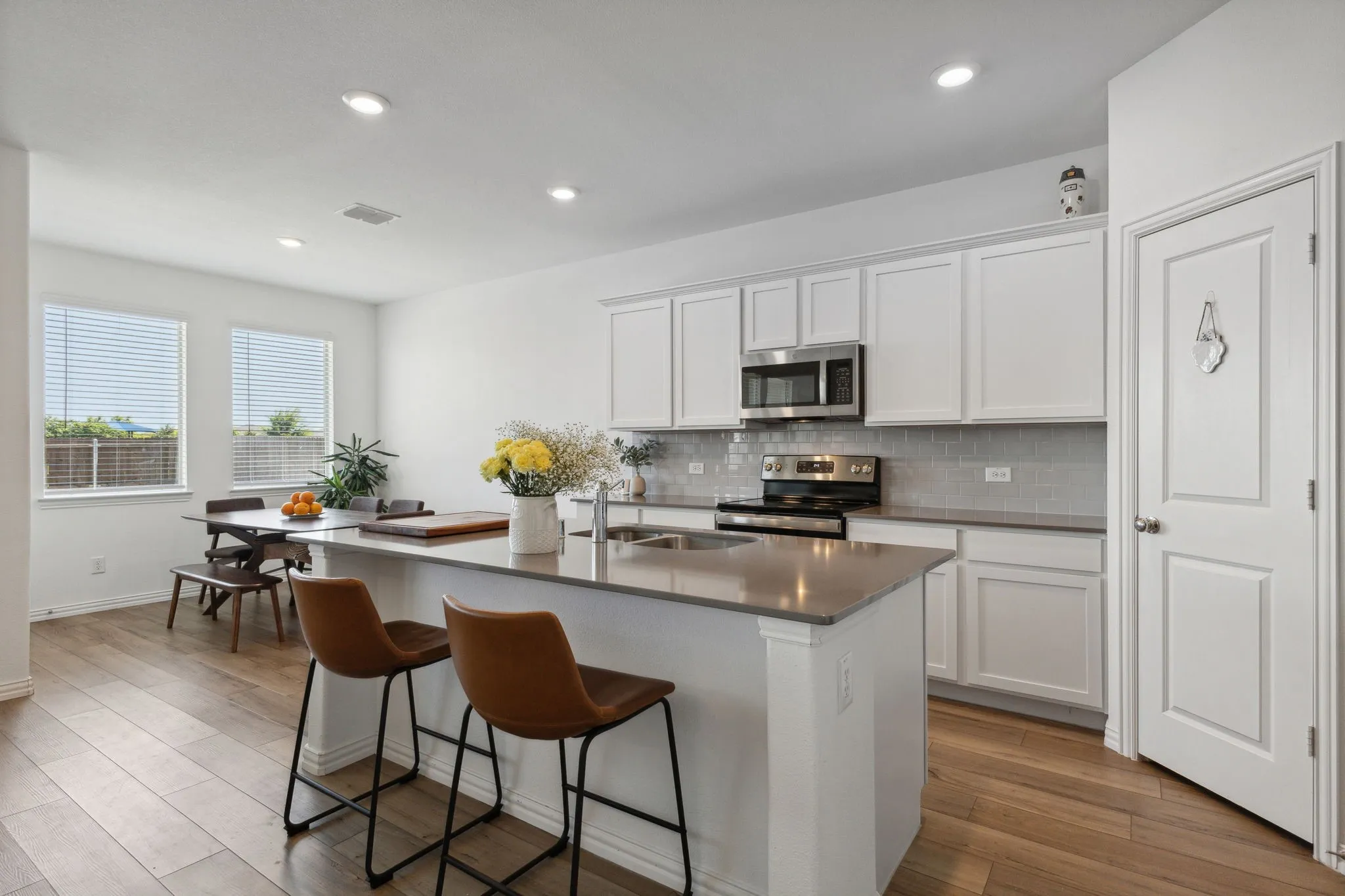 Kitchen featuring a central island, stainless steel appliances, white cabinetry, a subway tile backsplash, and wood-finish flooring