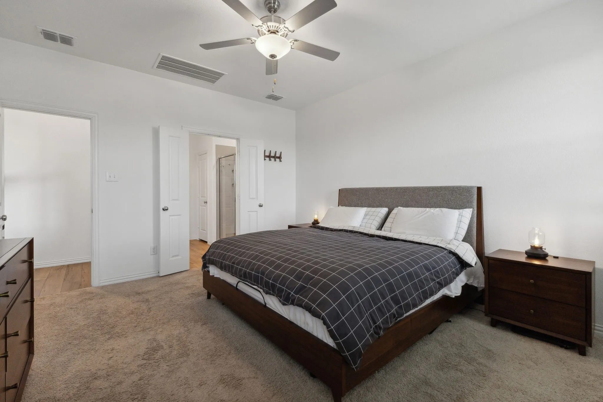 Bright bedroom featuring light-colored walls and plush carpeting