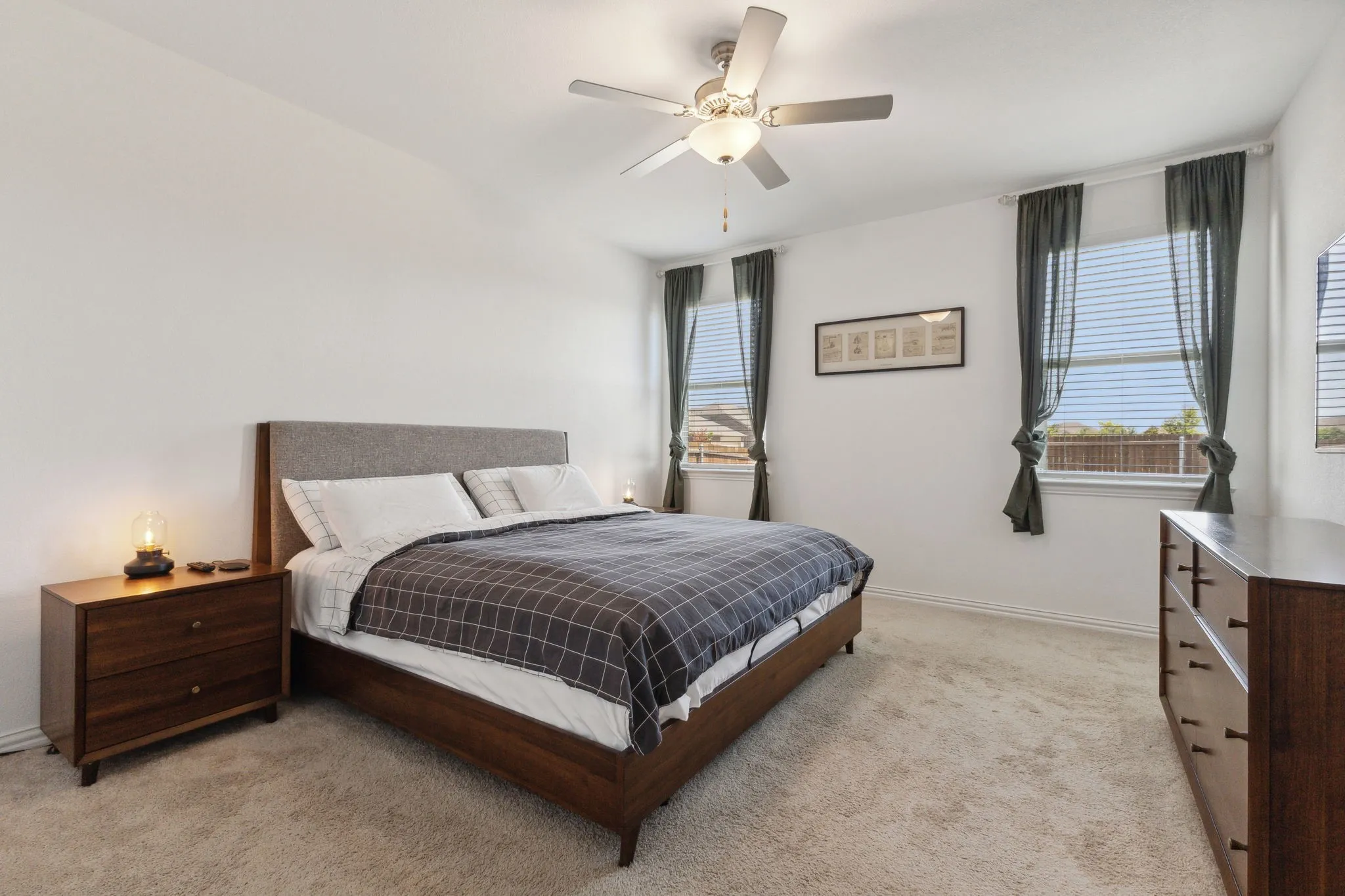 Carpeted room featuring a ceiling fan with integrated lighting, multiple windows with blinds, and white walls