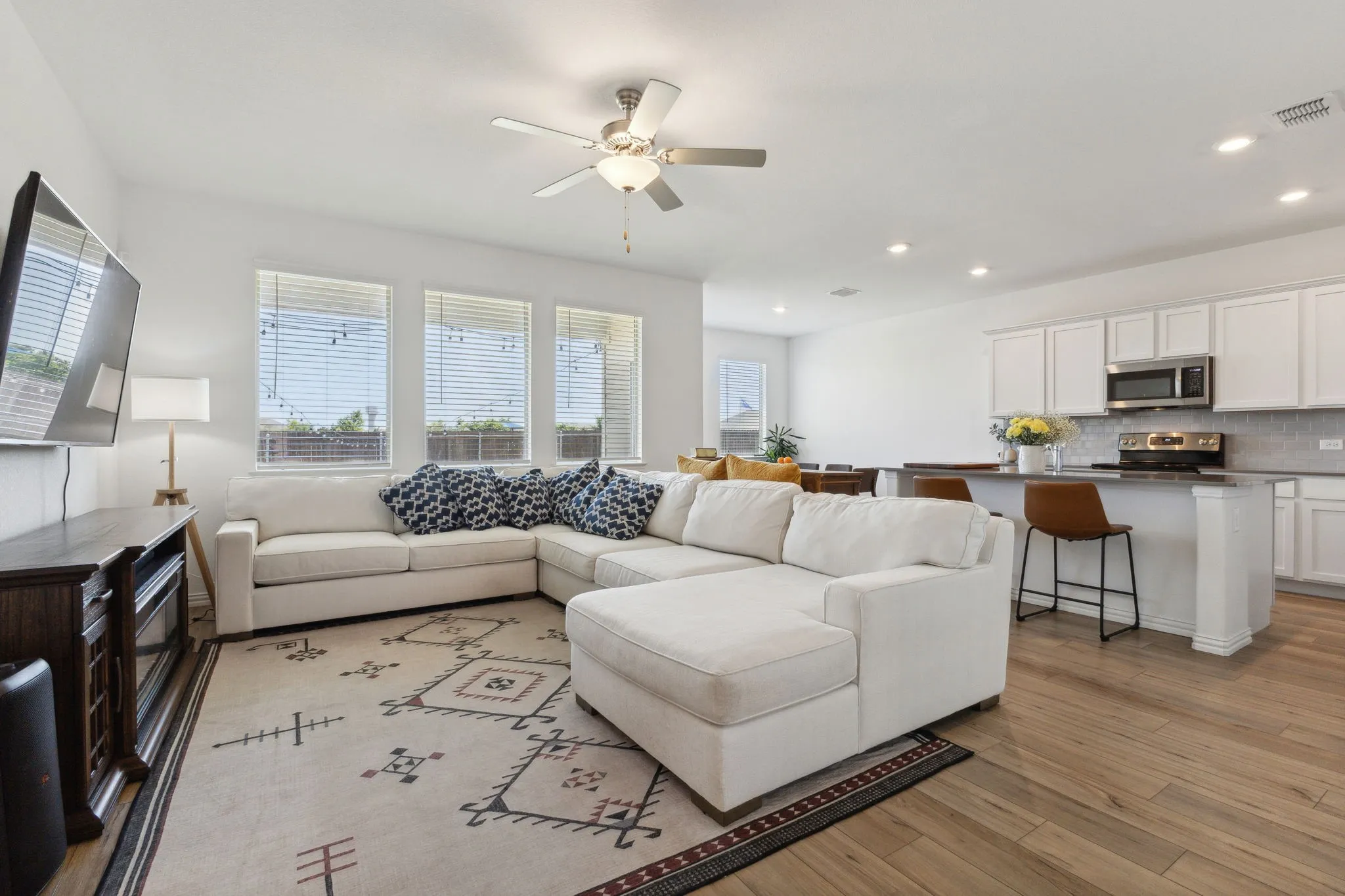 Open-concept living area featuring wood-finish flooring, recessed lighting, a ceiling fan, and multiple windows