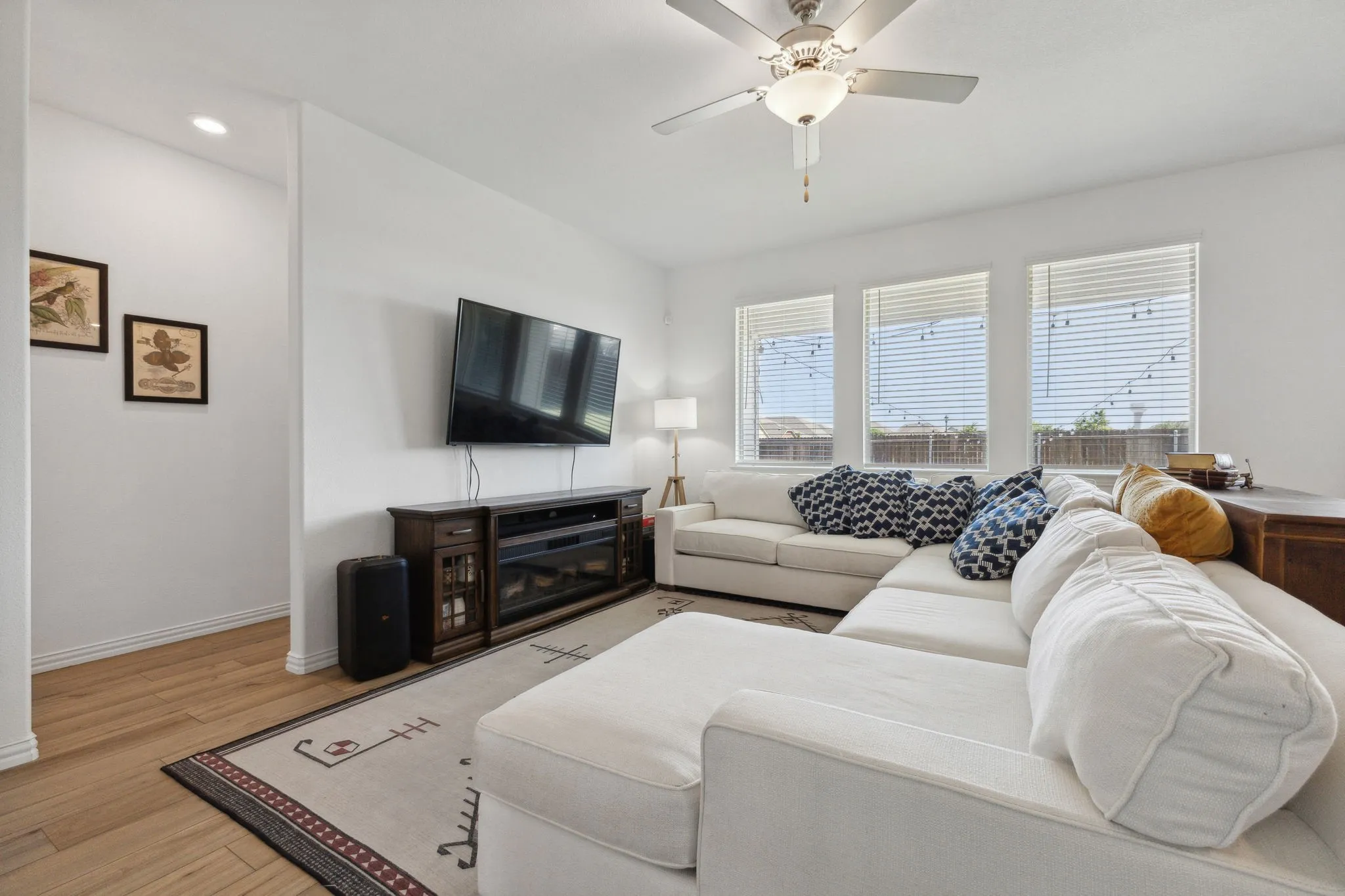 Spacious living area featuring light wood-finish flooring, recessed lighting, and a ceiling fan with integrated lighting