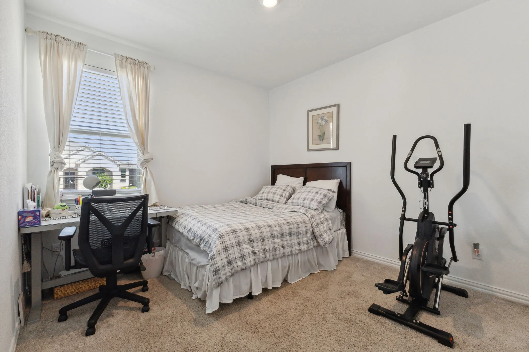 Carpeted room featuring a white painted wall, a dark wood-finish headboard, and a window with white blinds and drapes