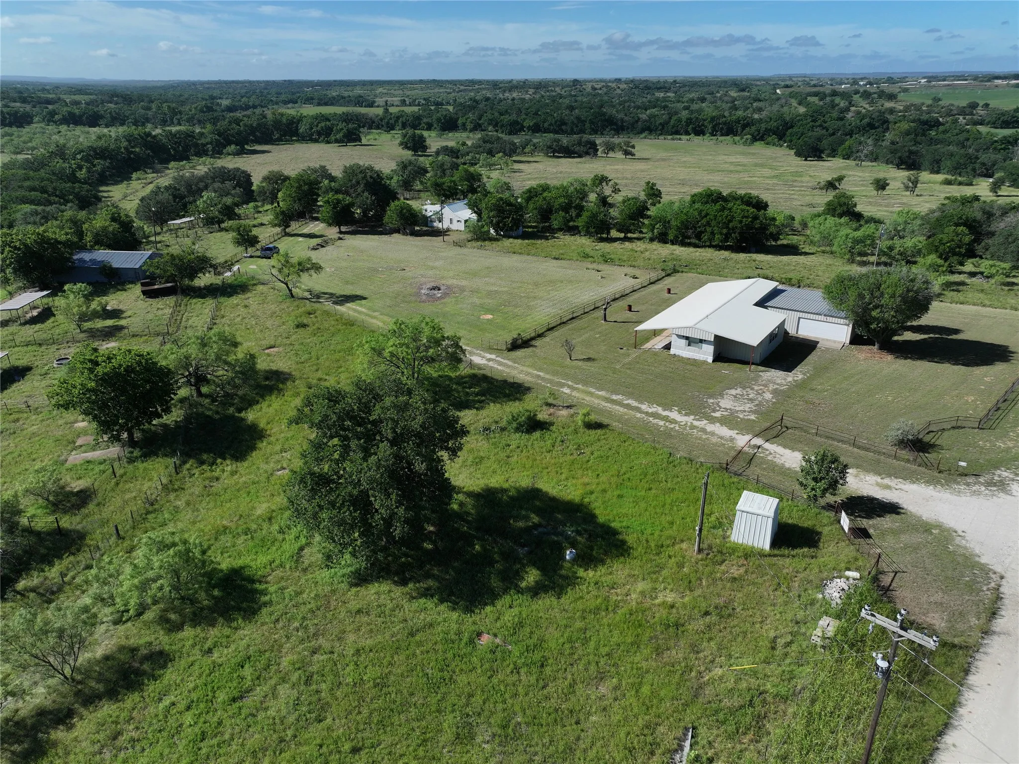 Expansive acreage featuring multiple structures, mature trees, open pastures, and a perimeter fence