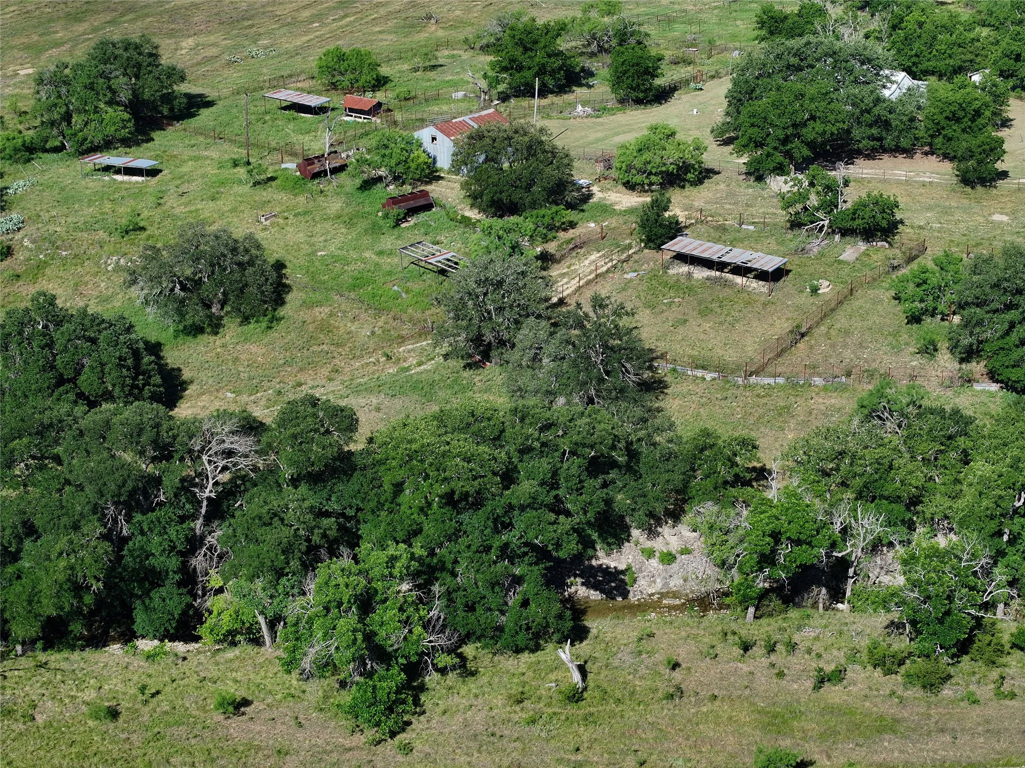 Expansive acreage featuring multiple outbuildings, mature trees, and a natural water feature