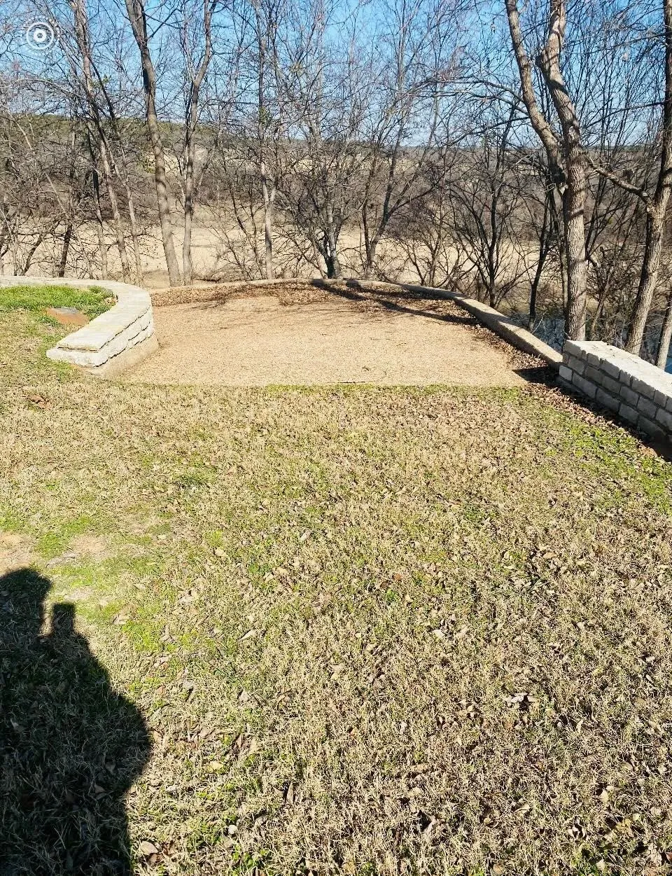 Terraced yard area featuring a gravel pad and stone retaining walls