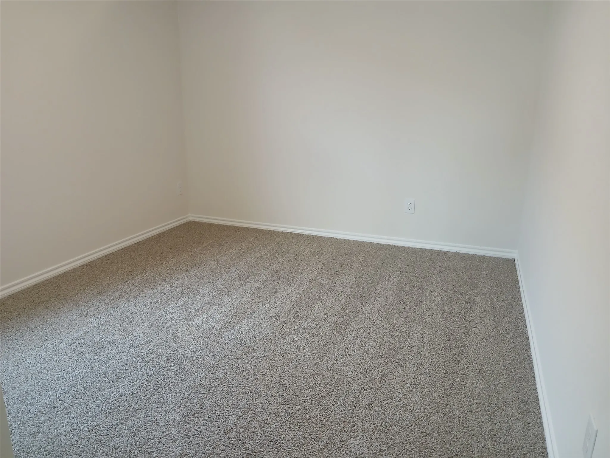 Neutral wall tones complement the neutral-toned carpeting, featuring clean baseboards and an electrical outlet
