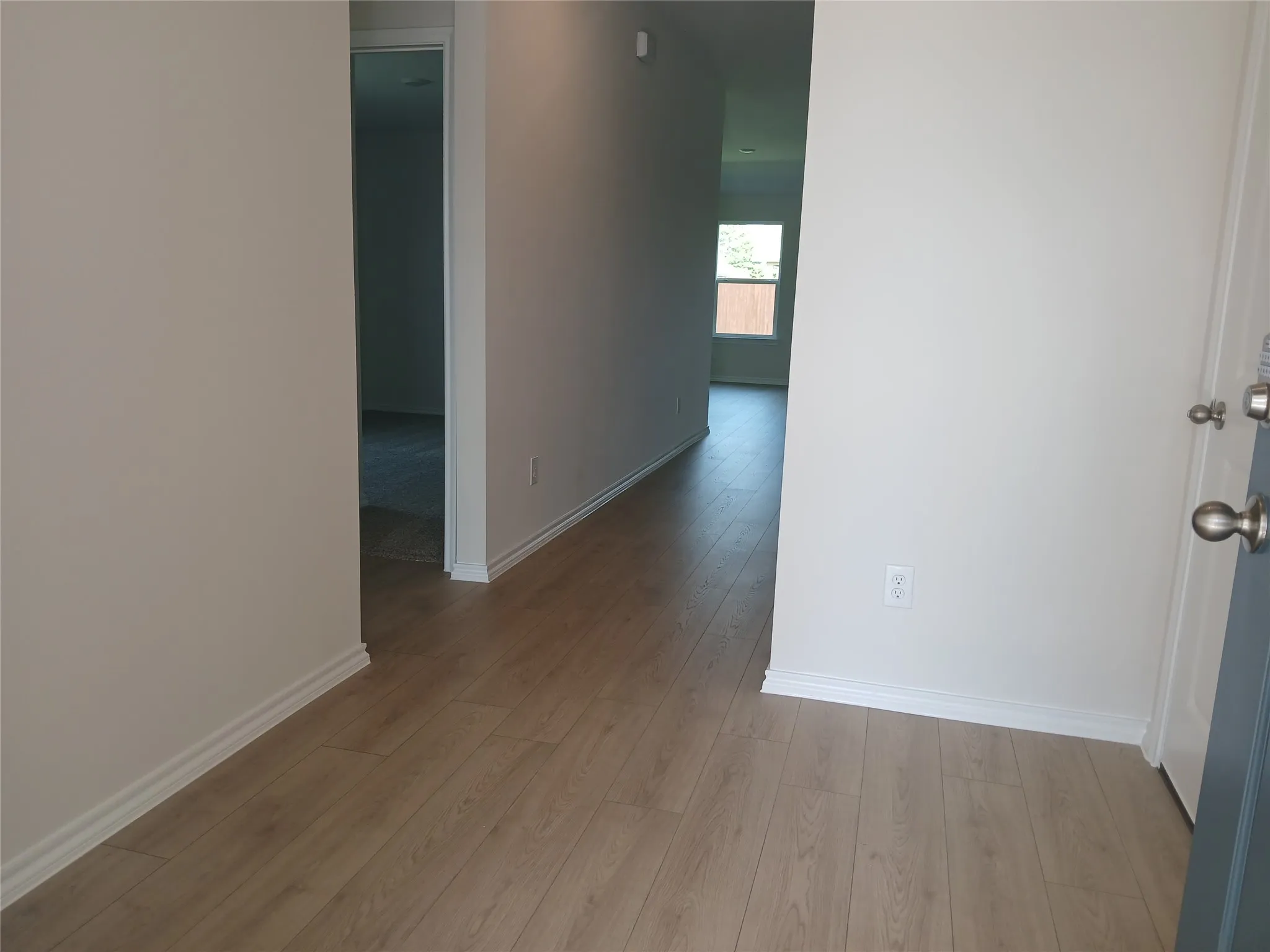 Entryway featuring wood-finish flooring, light neutral wall tones, white trim, and a satin nickel door knob