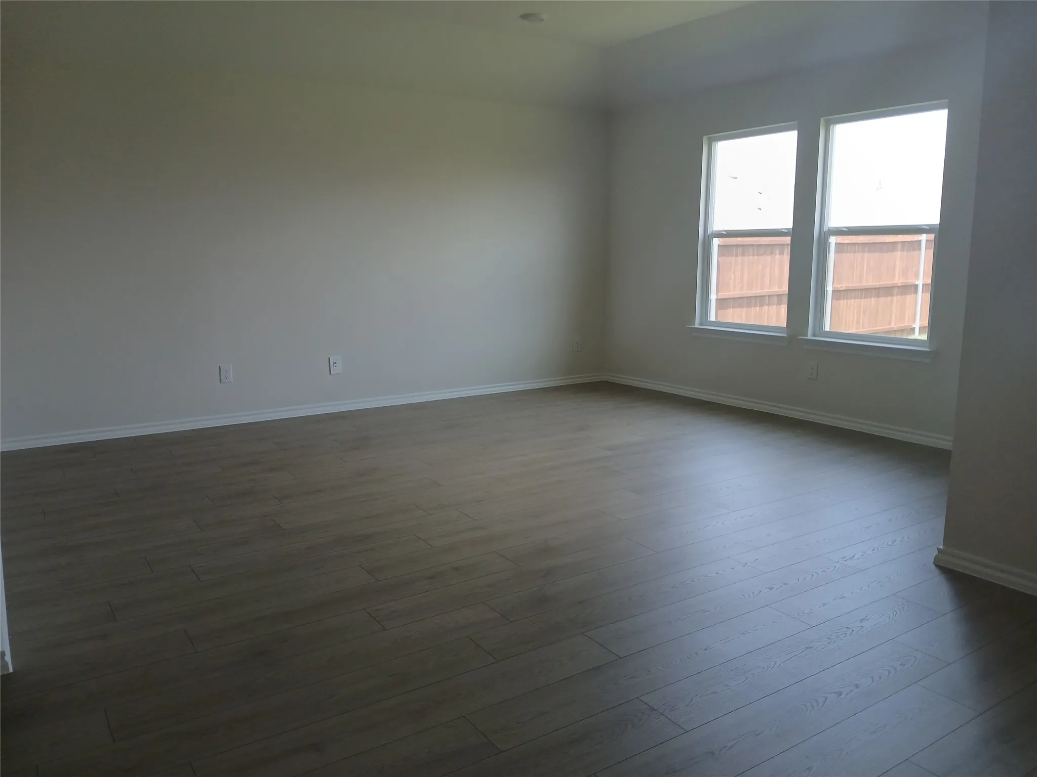 Spacious room featuring wood-finish flooring and neutral wall tones