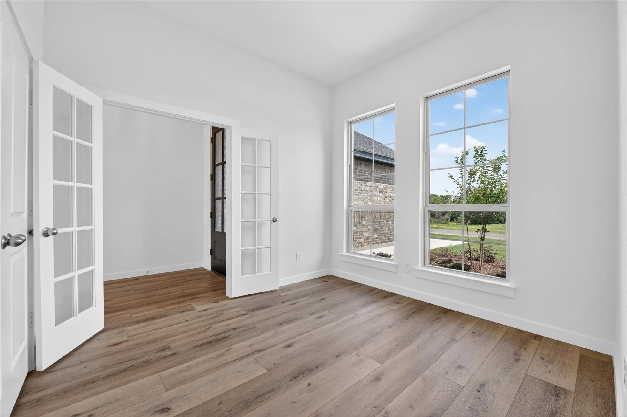Open-concept living area featuring wood-finish flooring, a stone-clad fireplace, and a ceiling fan with integrated lighting