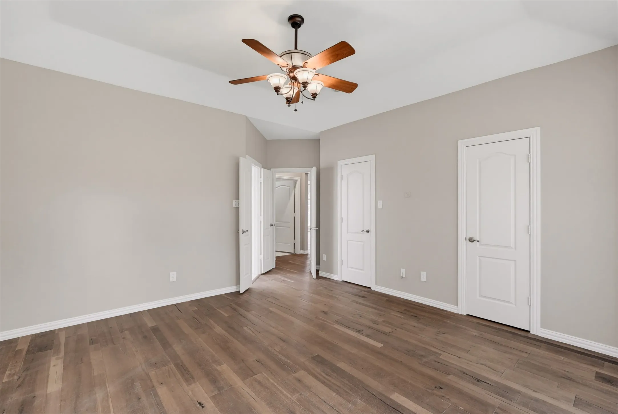 Spacious room featuring wood-finish flooring, light grey wall tones, and crisp white trim