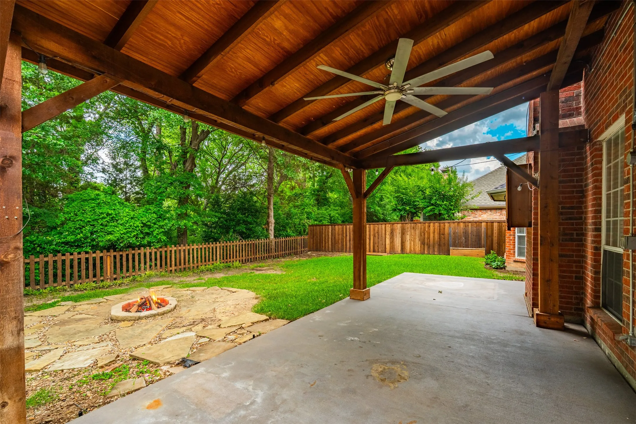 Covered patio featuring a wood-finish ceiling with a ceiling fan, concrete flooring, and brick exterior wall