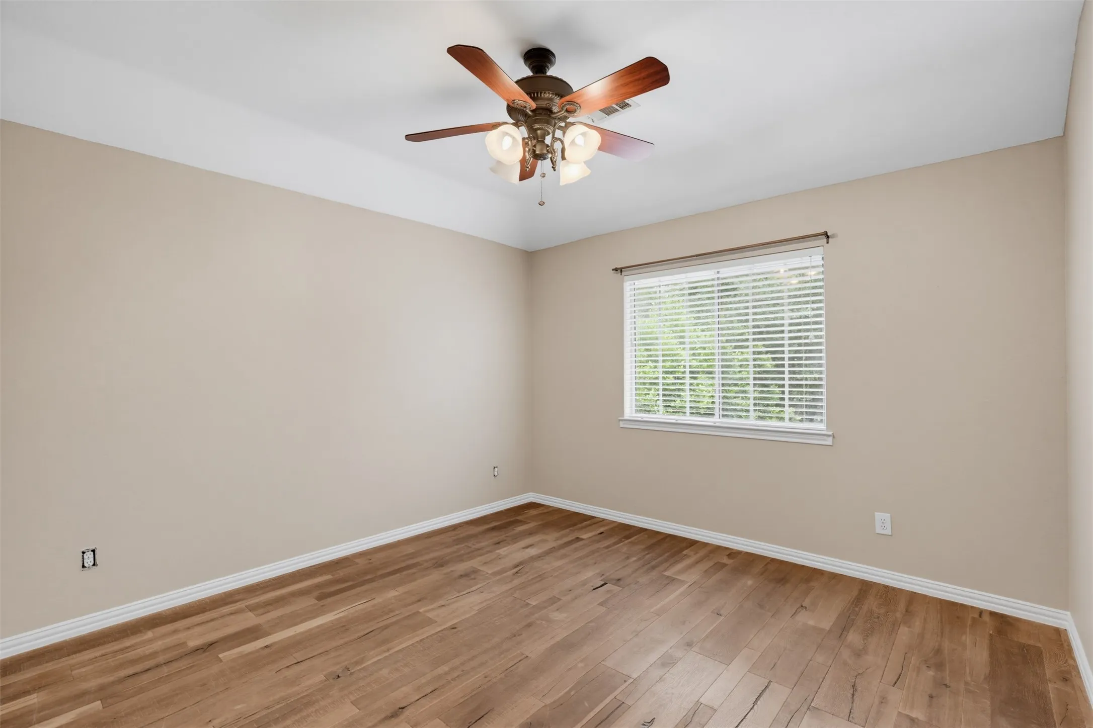 Room with wood-finish flooring, neutral wall tones, and white trim