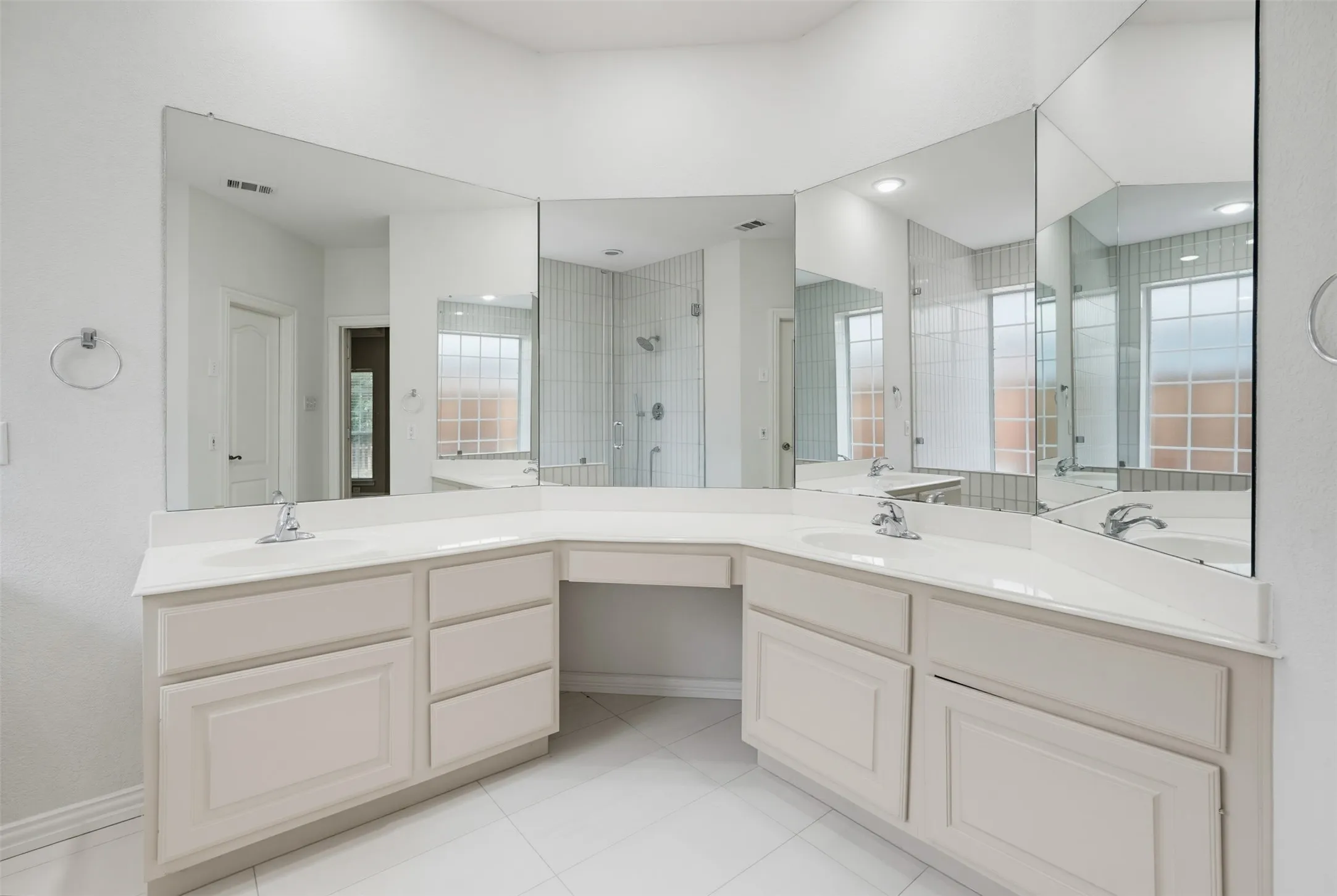 Expansive bathroom featuring a dual vanity with integrated sinks, white countertops, and extensive mirror coverage