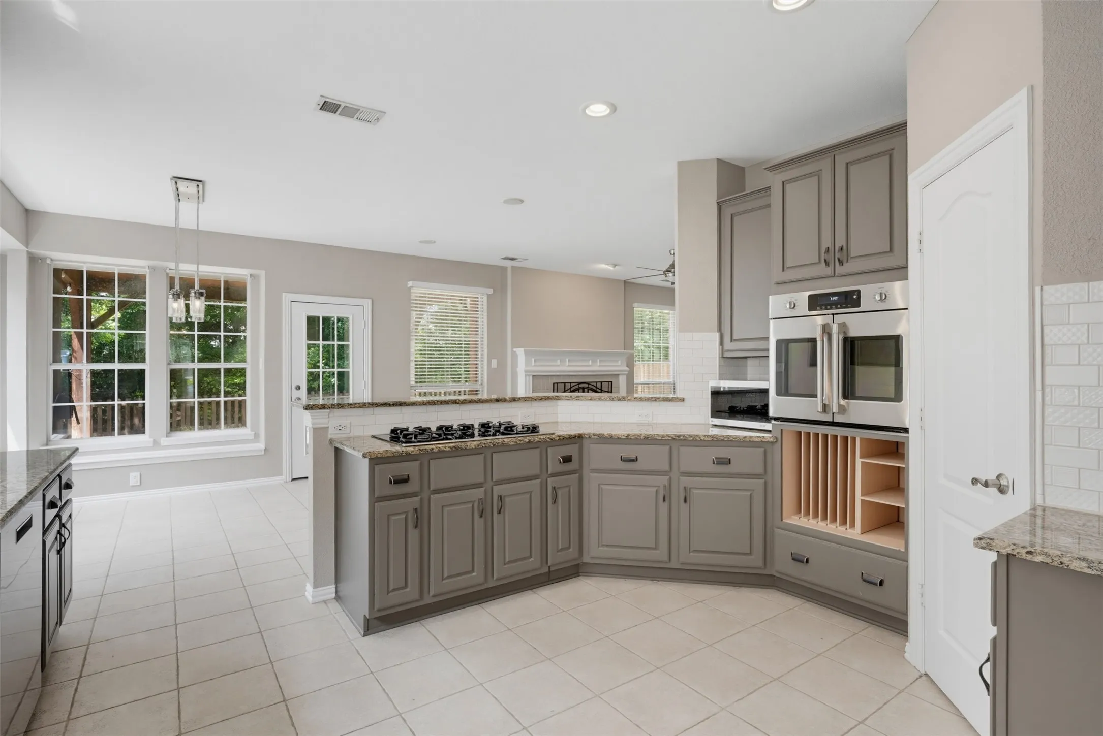 Kitchen featuring abundant gray cabinetry, stainless steel double ovens, a gas cooktop, granite countertops, and tile flooring