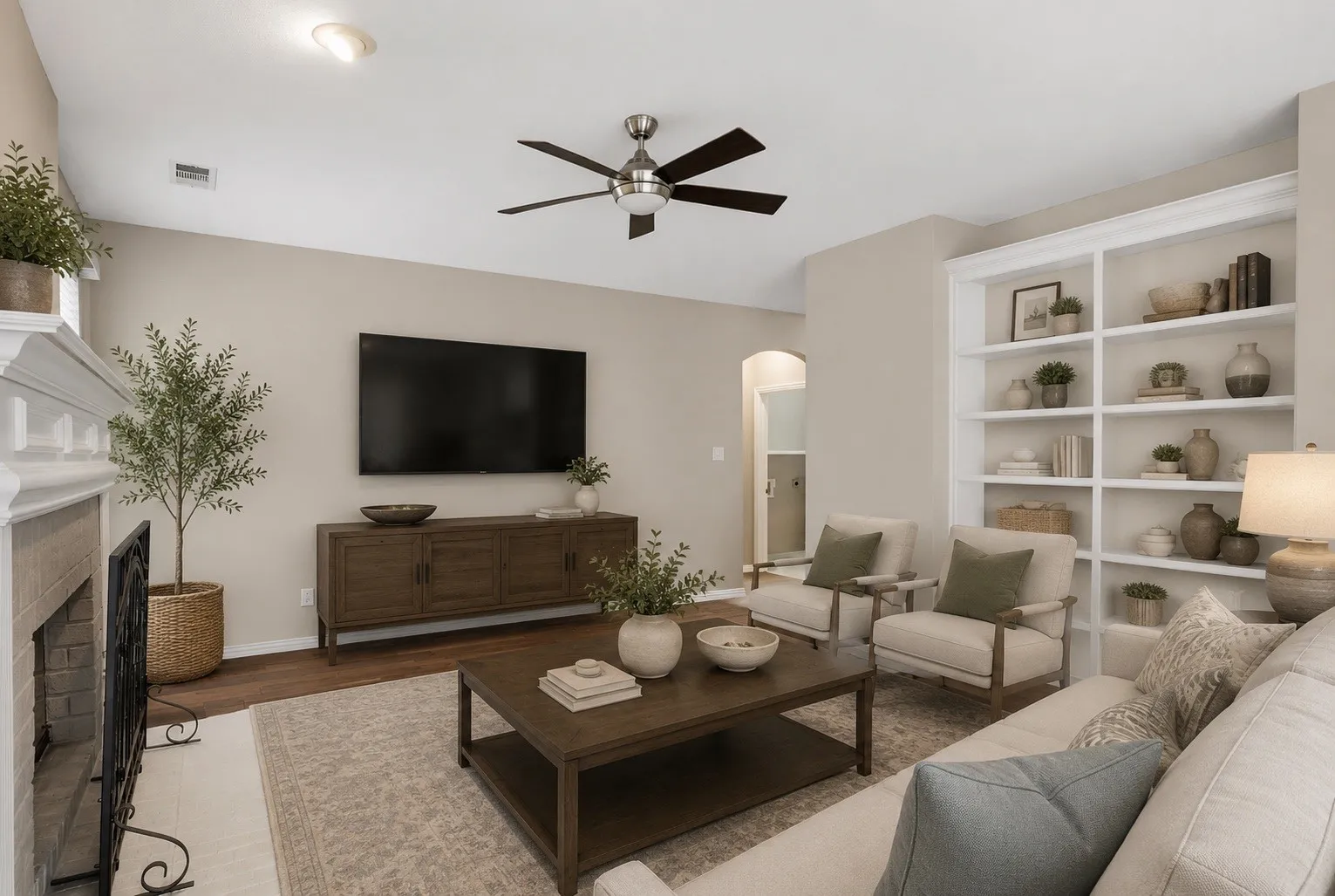 Living area featuring a fireplace with a detailed white mantel, dark wood-finish flooring, and a ceiling fan