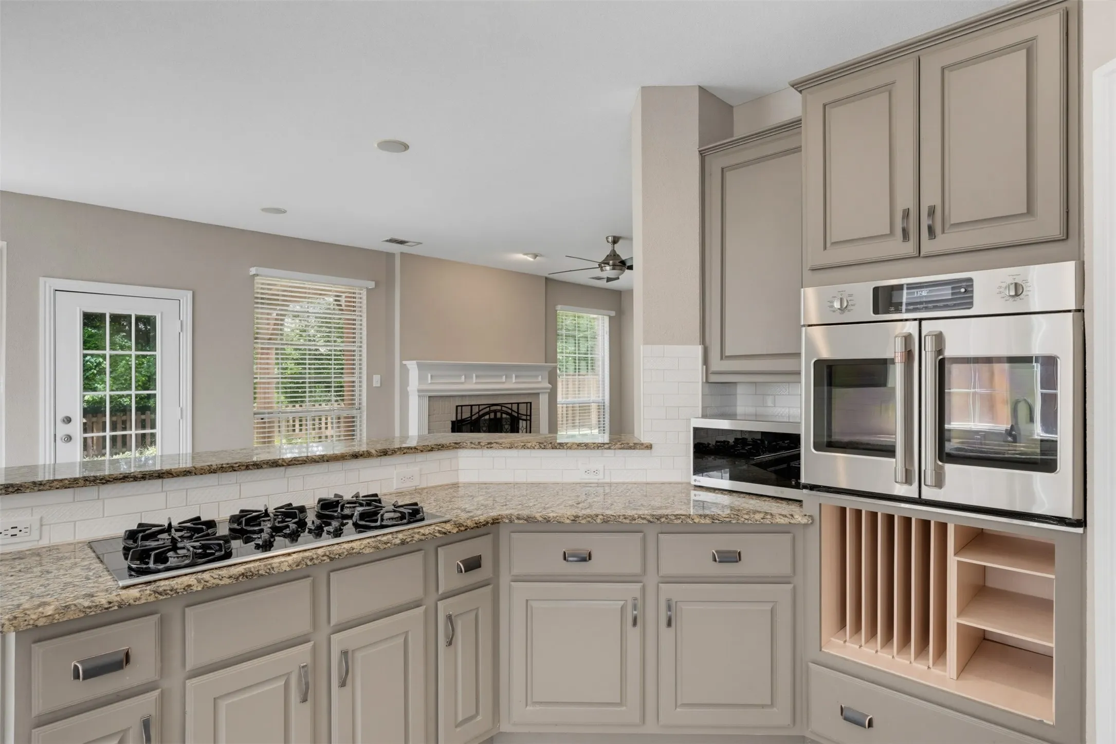 Kitchen featuring stone countertops, integrated cooktop, stainless steel double wall ovens, built-in microwave, and subway tile backsplash
