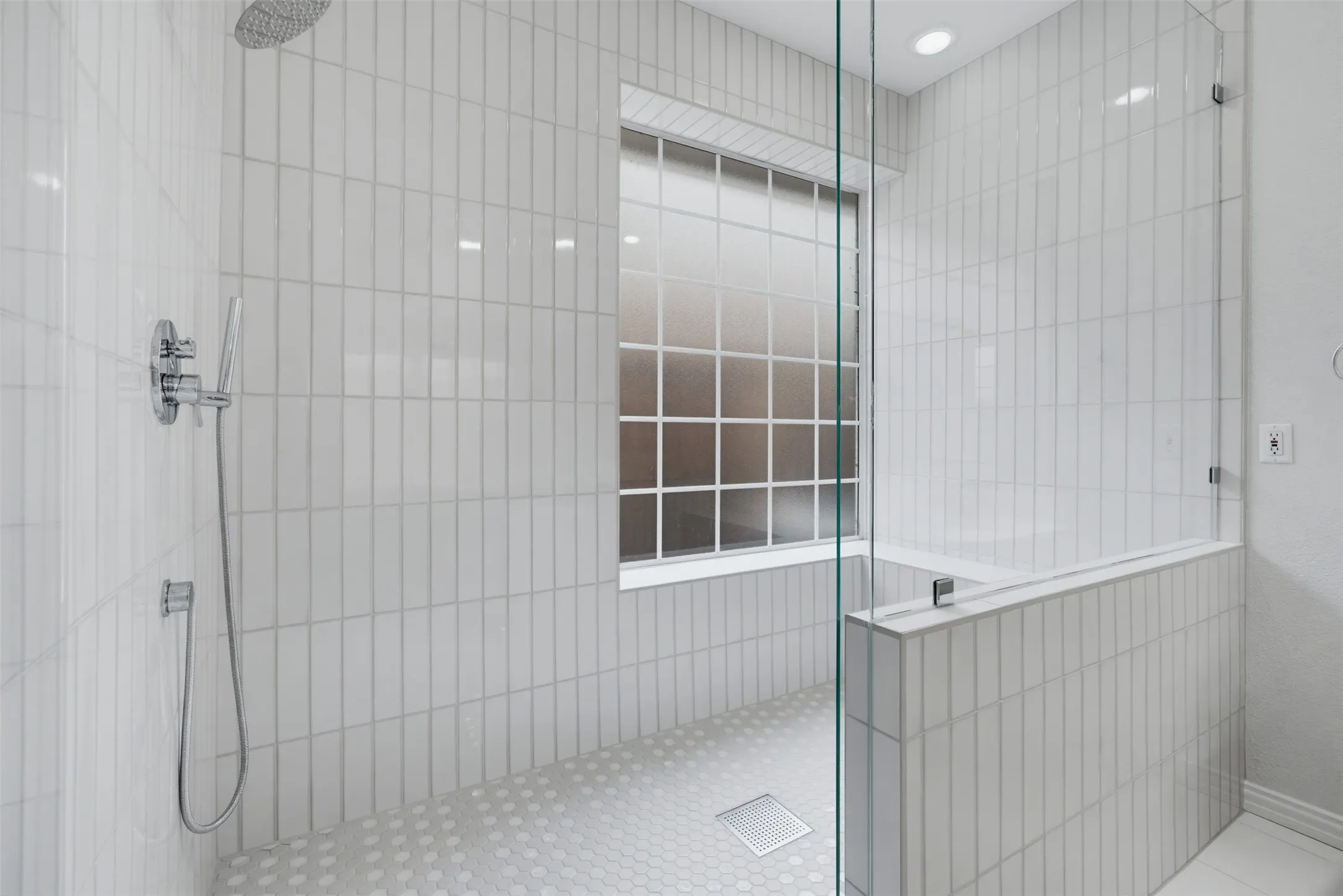 Spacious shower featuring floor-to-ceiling vertical subway tile, a chrome rainfall showerhead, and a handheld spray