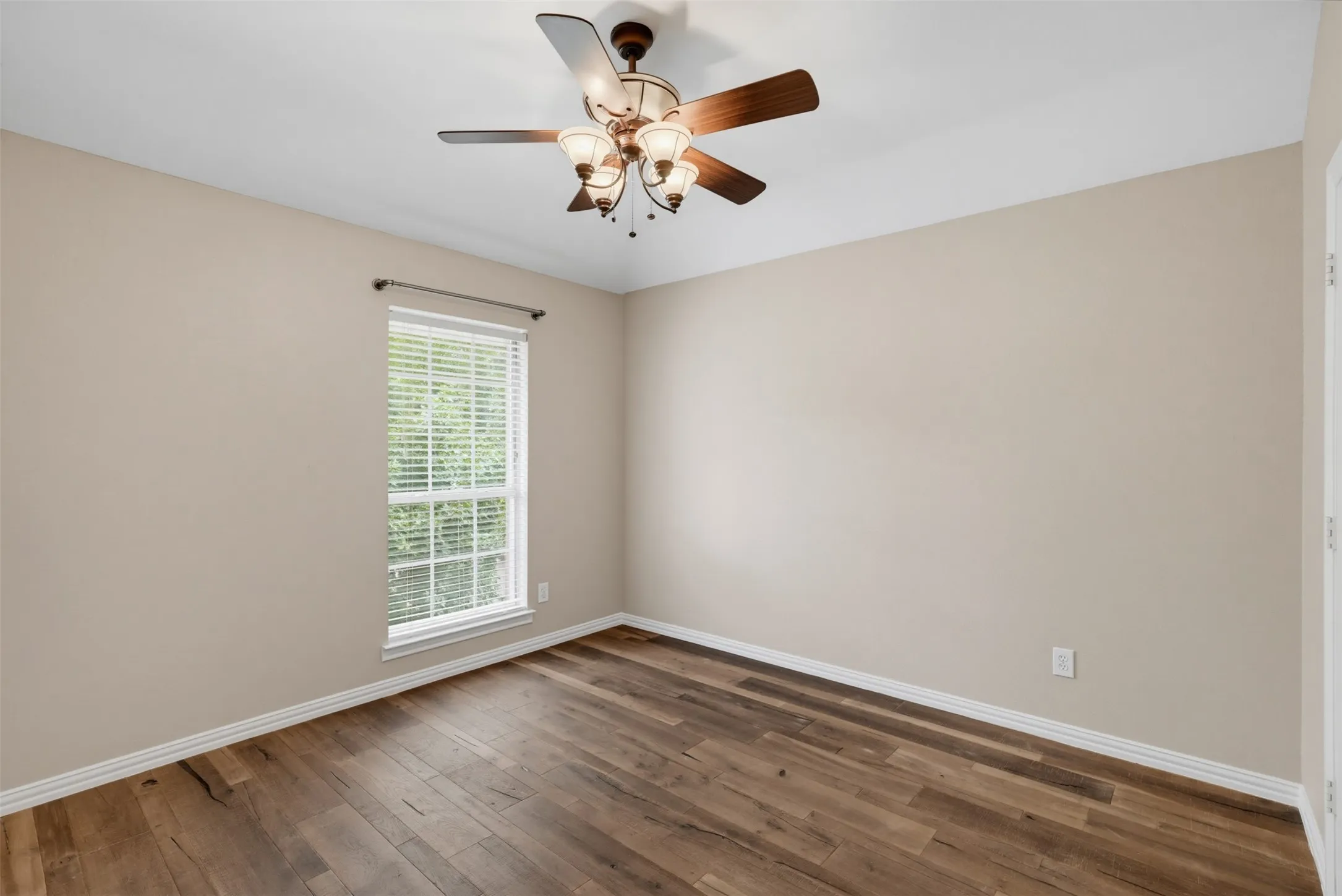 Interior room featuring wood-finish flooring, light neutral-toned walls, and white baseboards