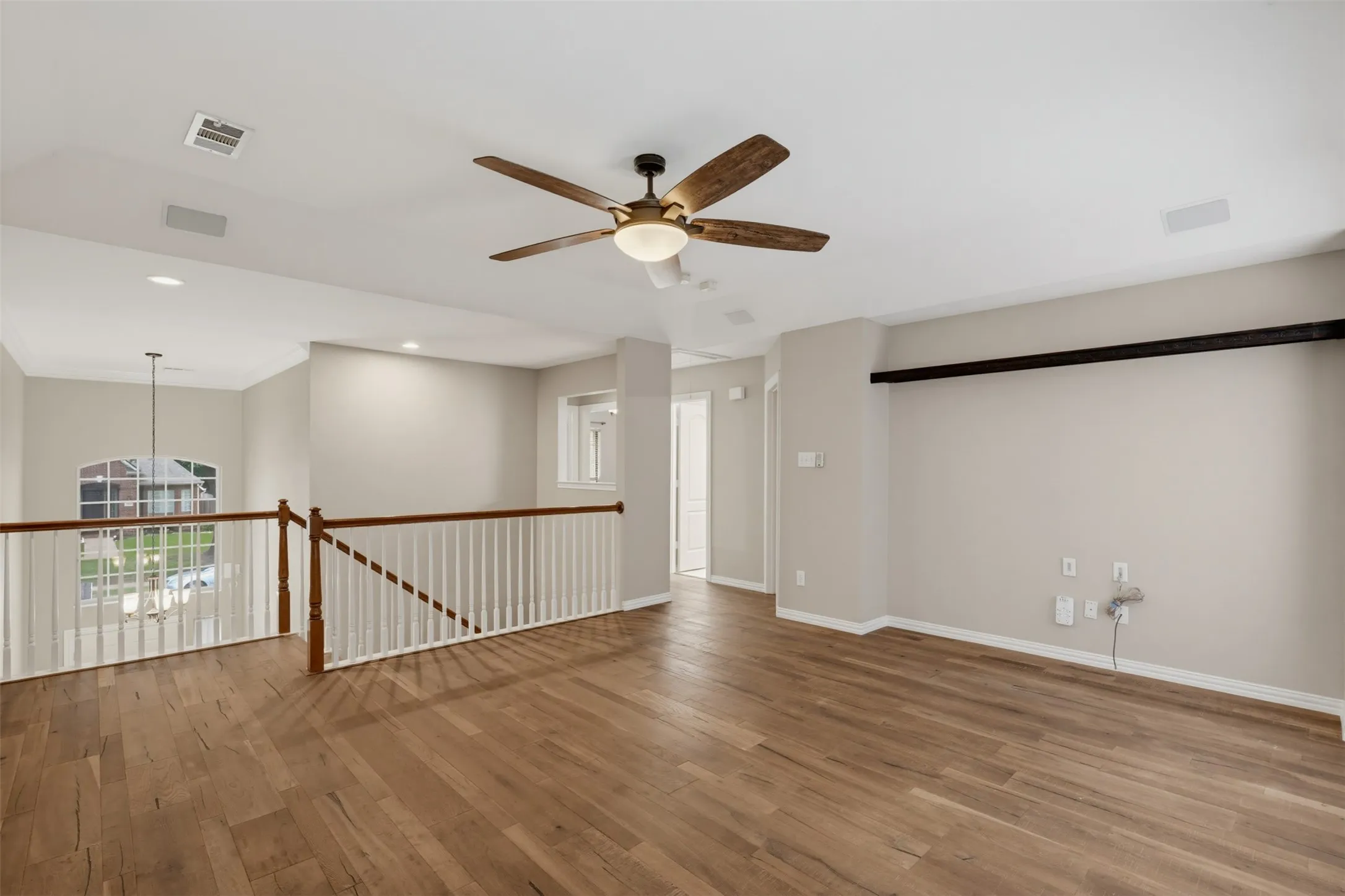 Open loft space featuring wood-finish flooring and a wood-bladed ceiling fan