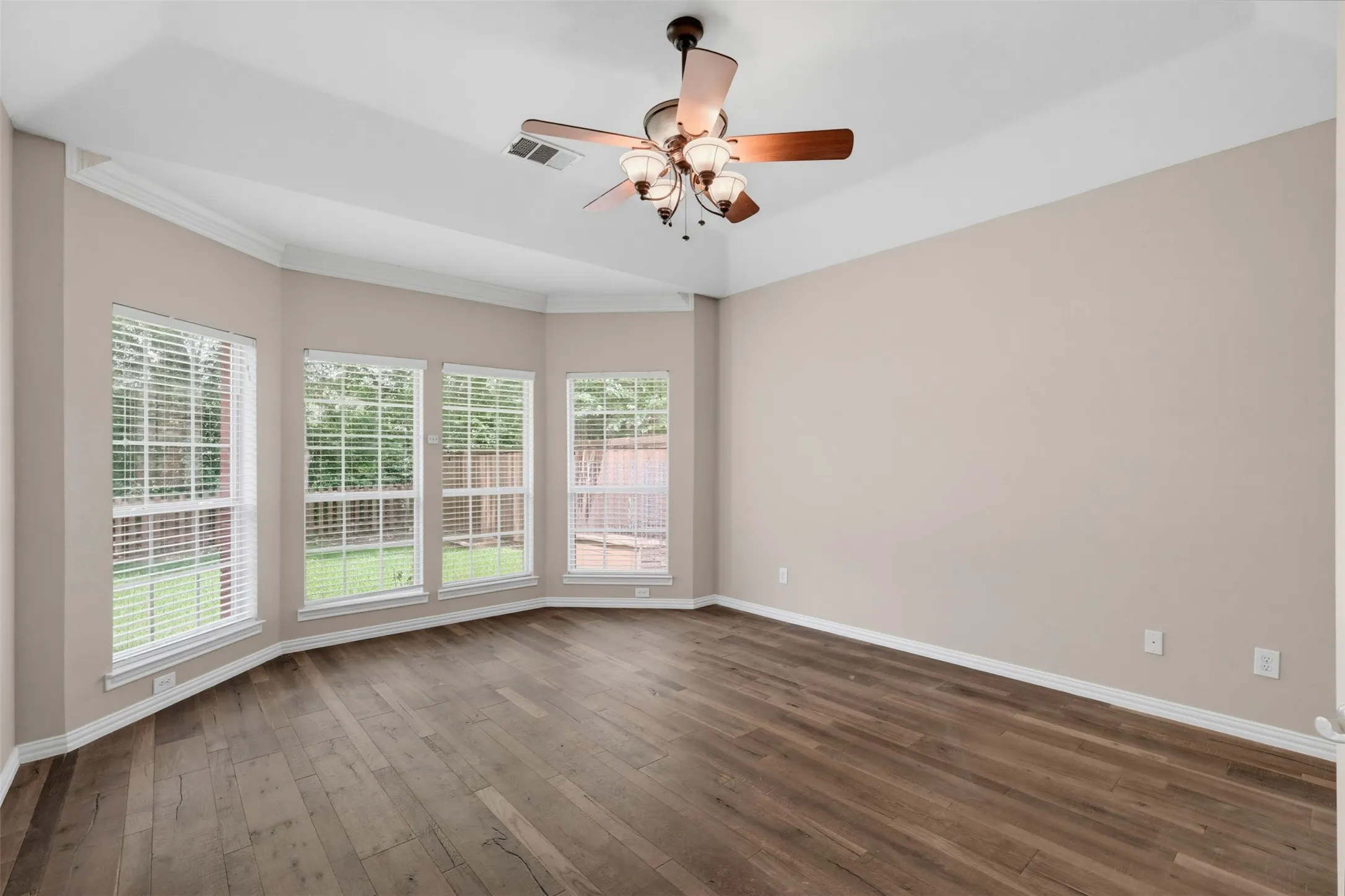 Spacious room featuring wood-finish flooring and a tray ceiling