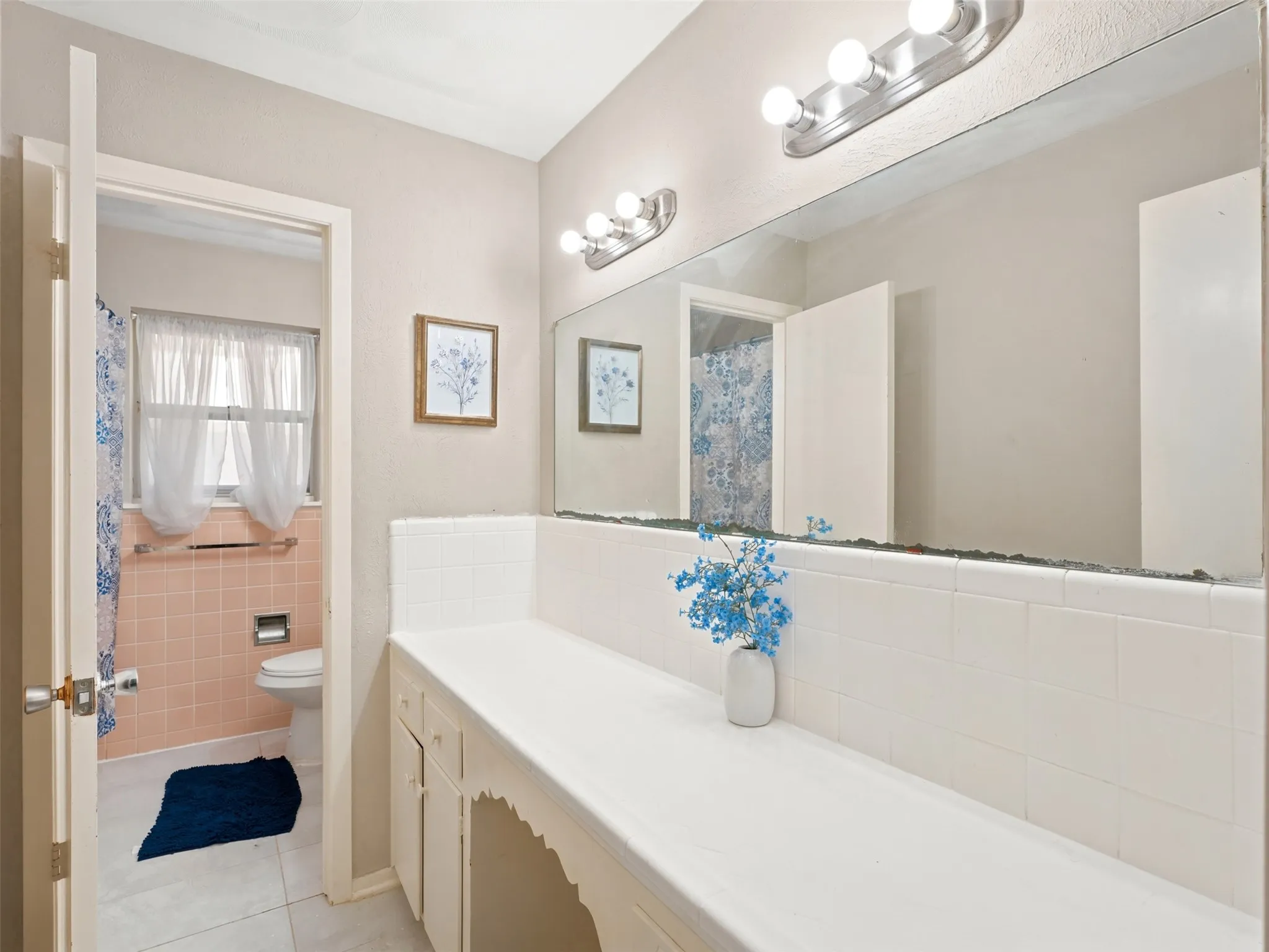 Long vanity with a built-in dressing area, white countertop, and white tiled backsplash