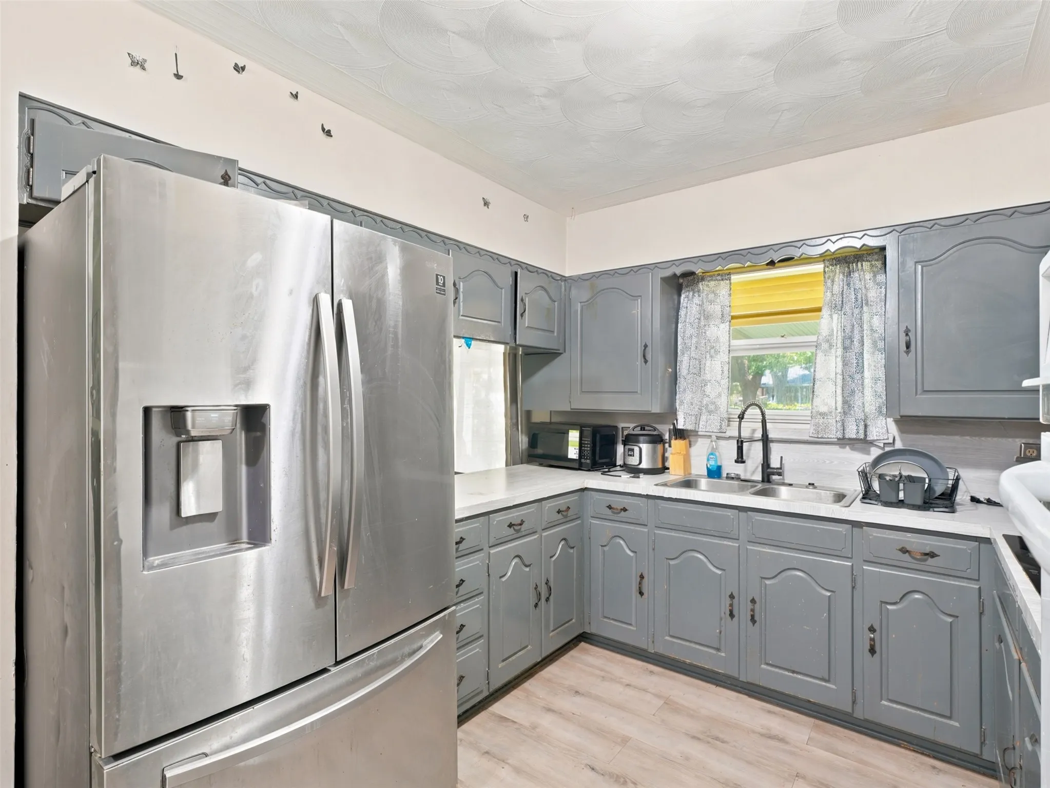 Kitchen featuring light gray cabinetry with decorative paneling and brass hardware