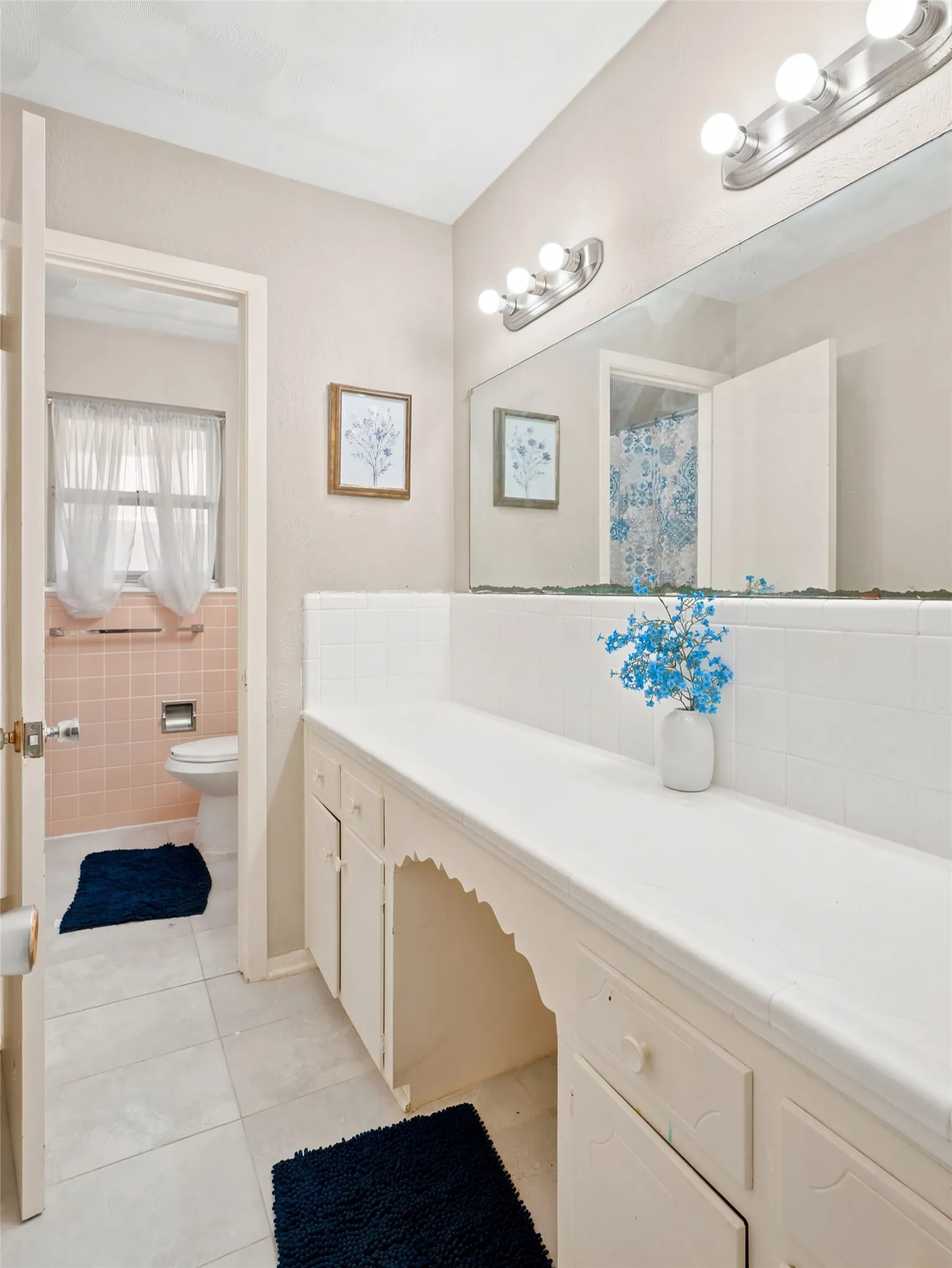 Bathroom vanity with extensive counter space, lower cabinetry, and an integrated mirror spanning the wall