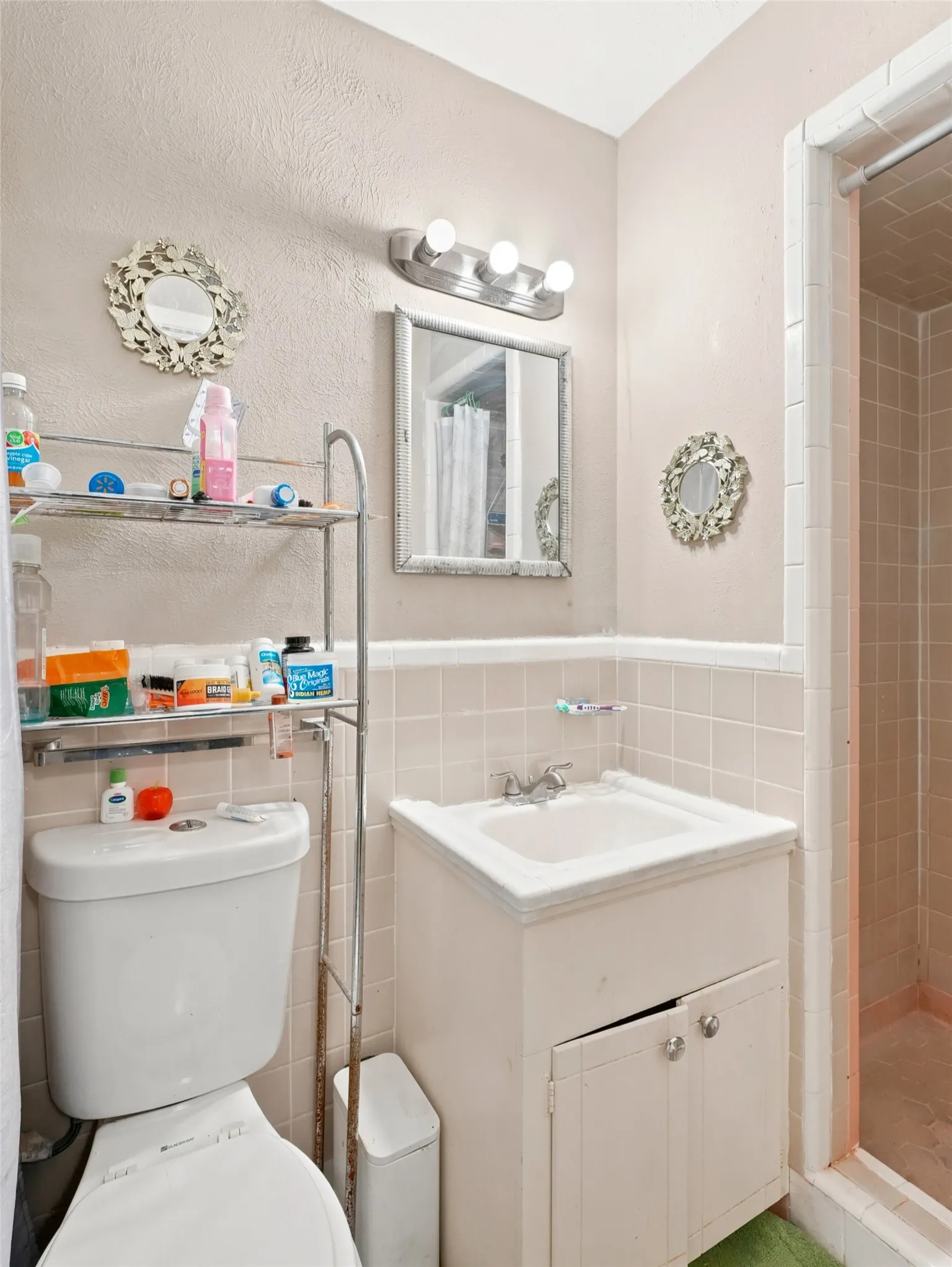 Compact bathroom featuring a shower stall, a single vanity with storage, and square wall tiling