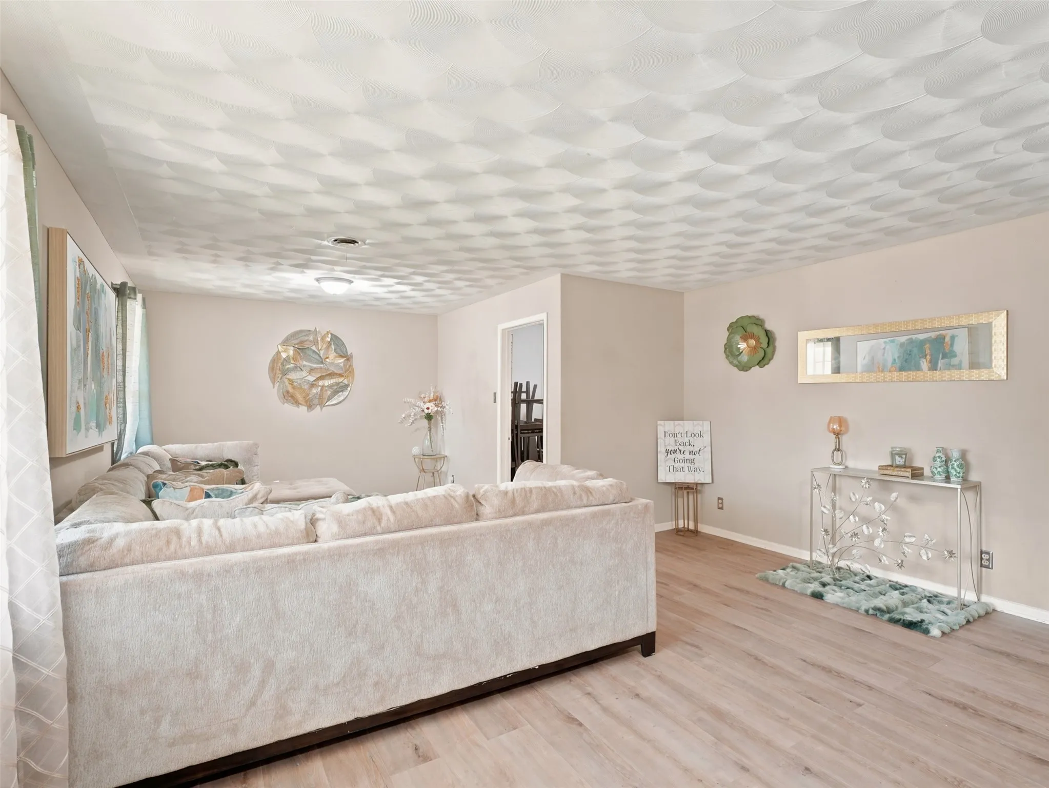 Spacious room featuring light-toned walls, wood-finish flooring, and a textured ceiling