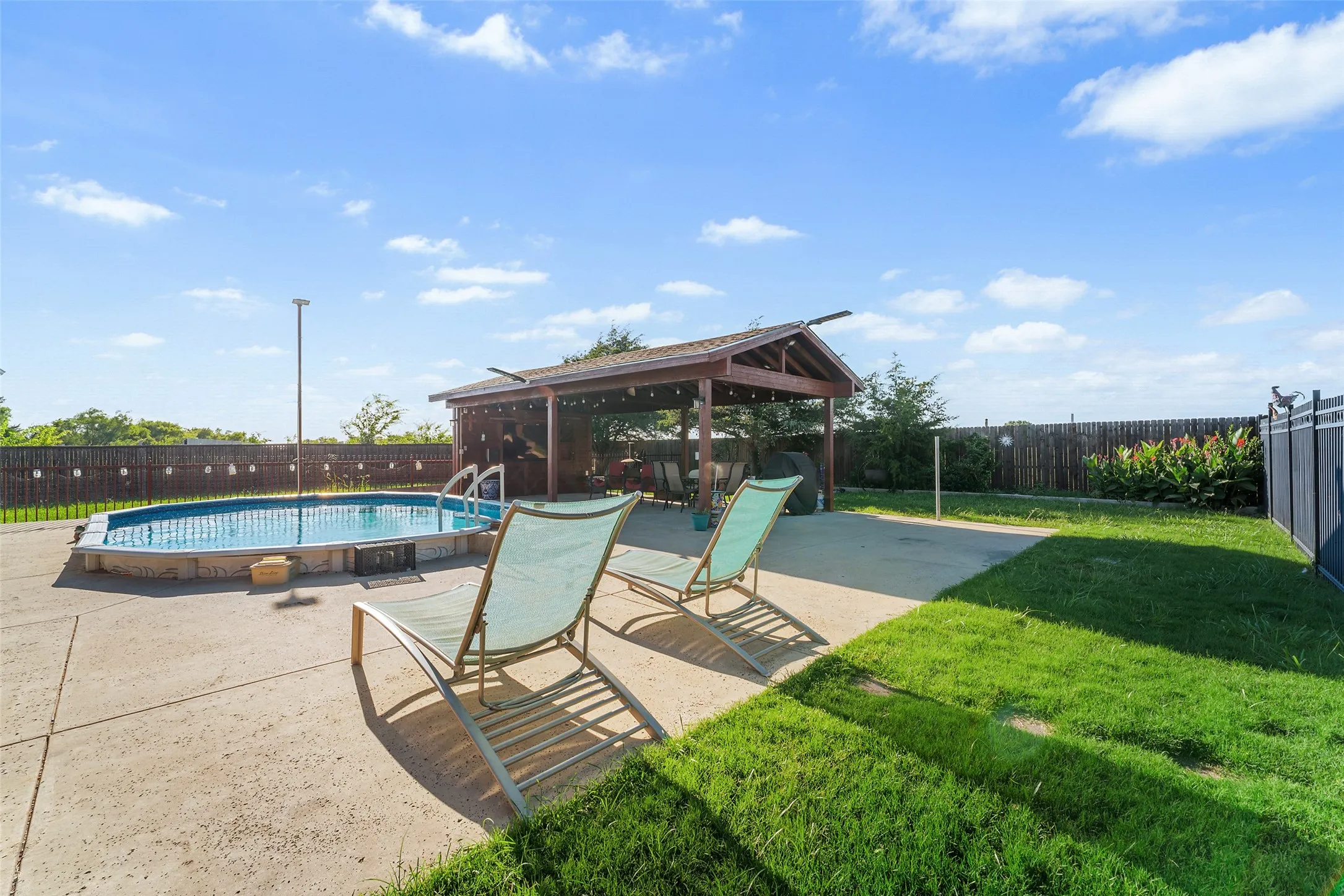 Backyard entertaining space featuring an above-ground pool, a covered gazebo, concrete patio, and a fenced perimeter