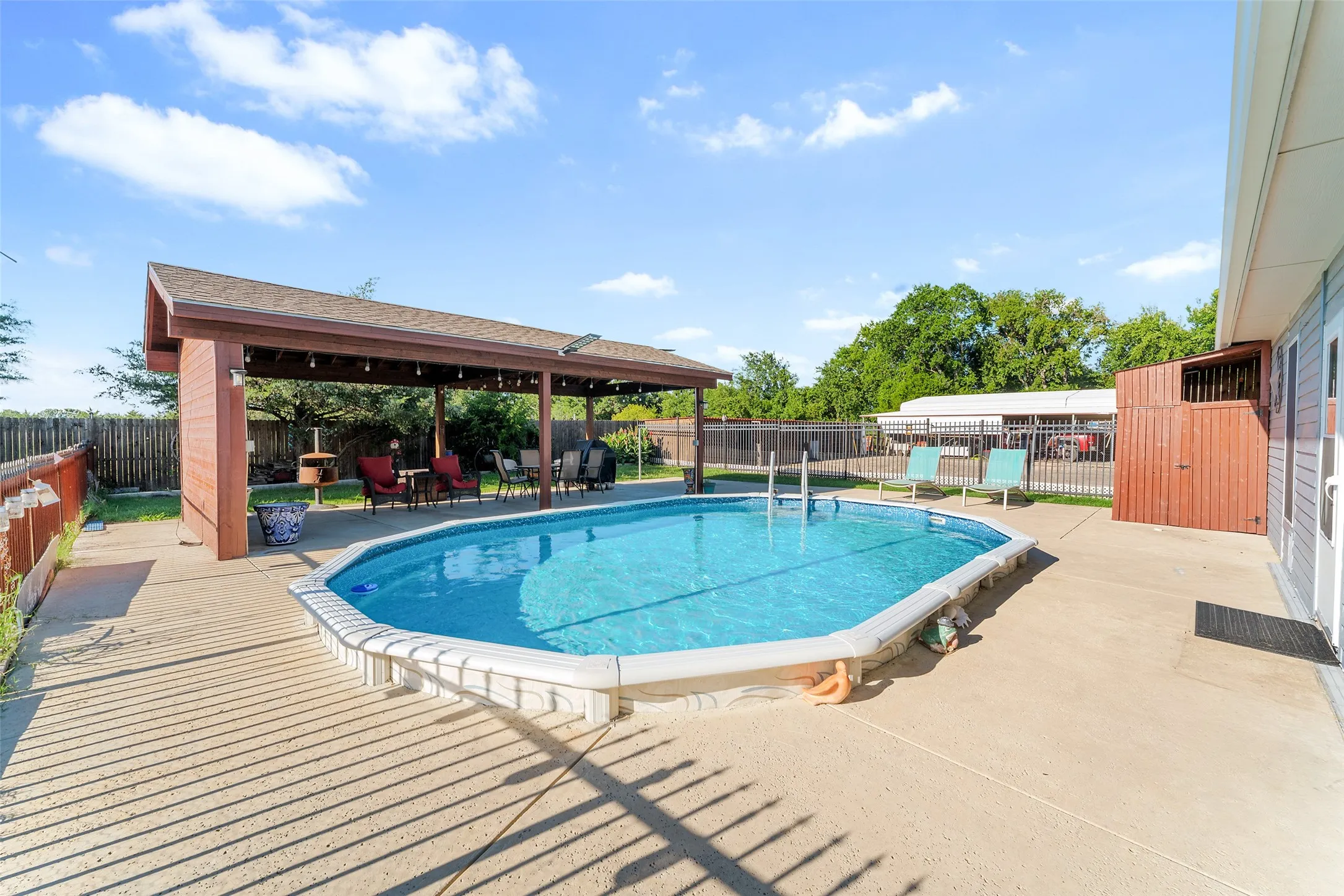 Backyard featuring an in-ground swimming pool, an expansive concrete patio, and a covered pergola